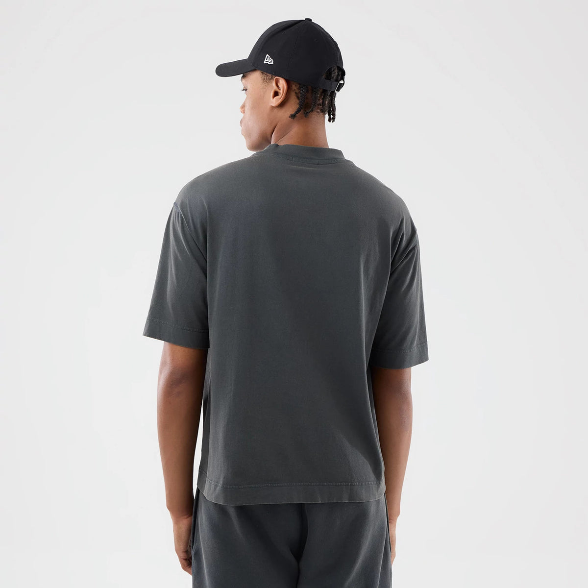New Era LA Dodgers MLB Washed Dark Grey T-Shirt, back view on-model showing the plain dark grey back and loose fit of the shirt, paired with a black cap featuring a small embroidered New Era logo on the side.