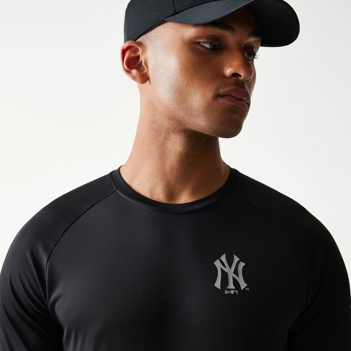 New Era New York Yankees MLB Reflective Black T-Shirt, front view on-model showing the reflective New York Yankees logo printed on the left chest and a casual fit styled with a black cap.