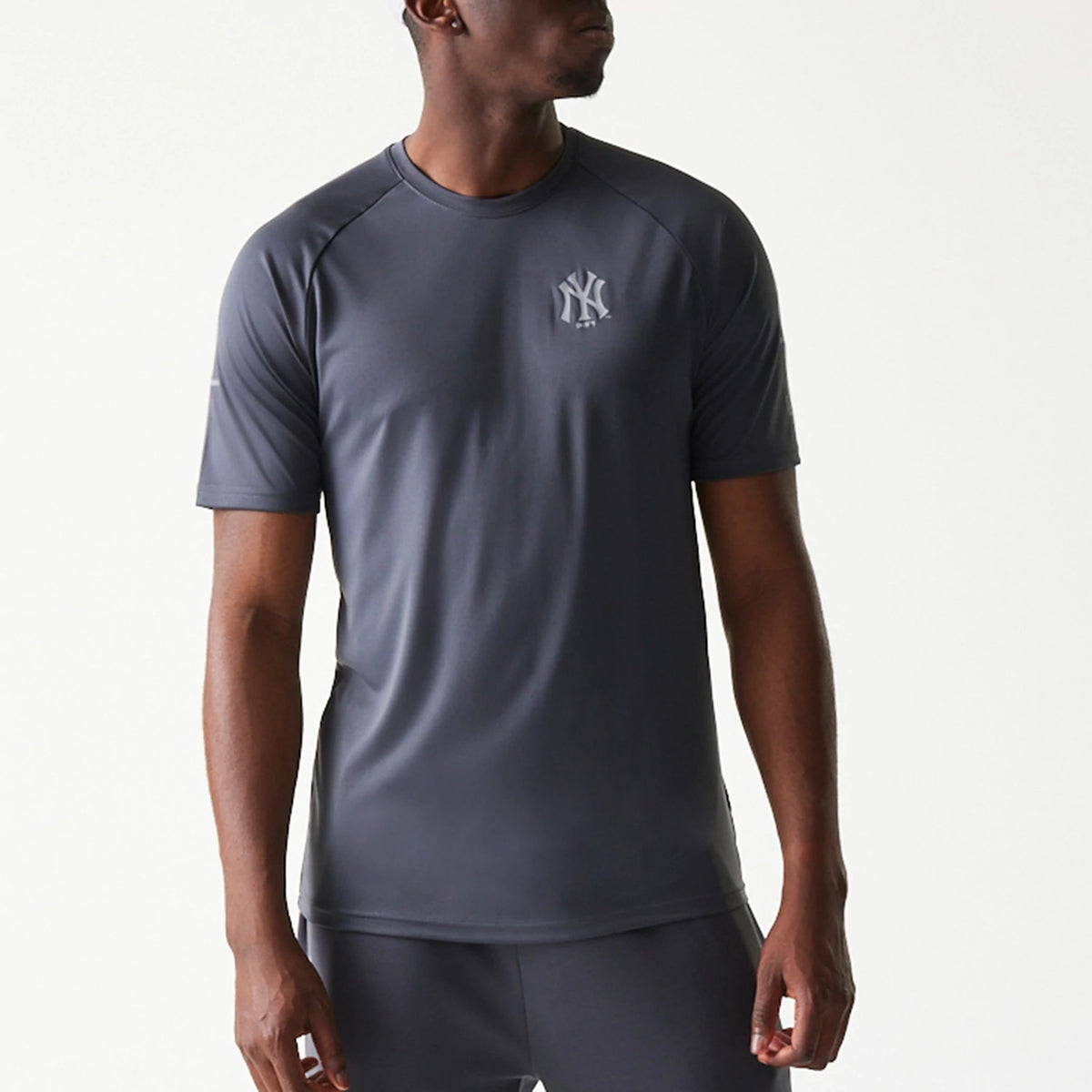 New Era New York Yankees MLB Dark Grey T-Shirt, front view on-model showing the dark grey short-sleeve design with a small raised New York Yankees logo on the left chest and raglan sleeves enhancing the sporty look.