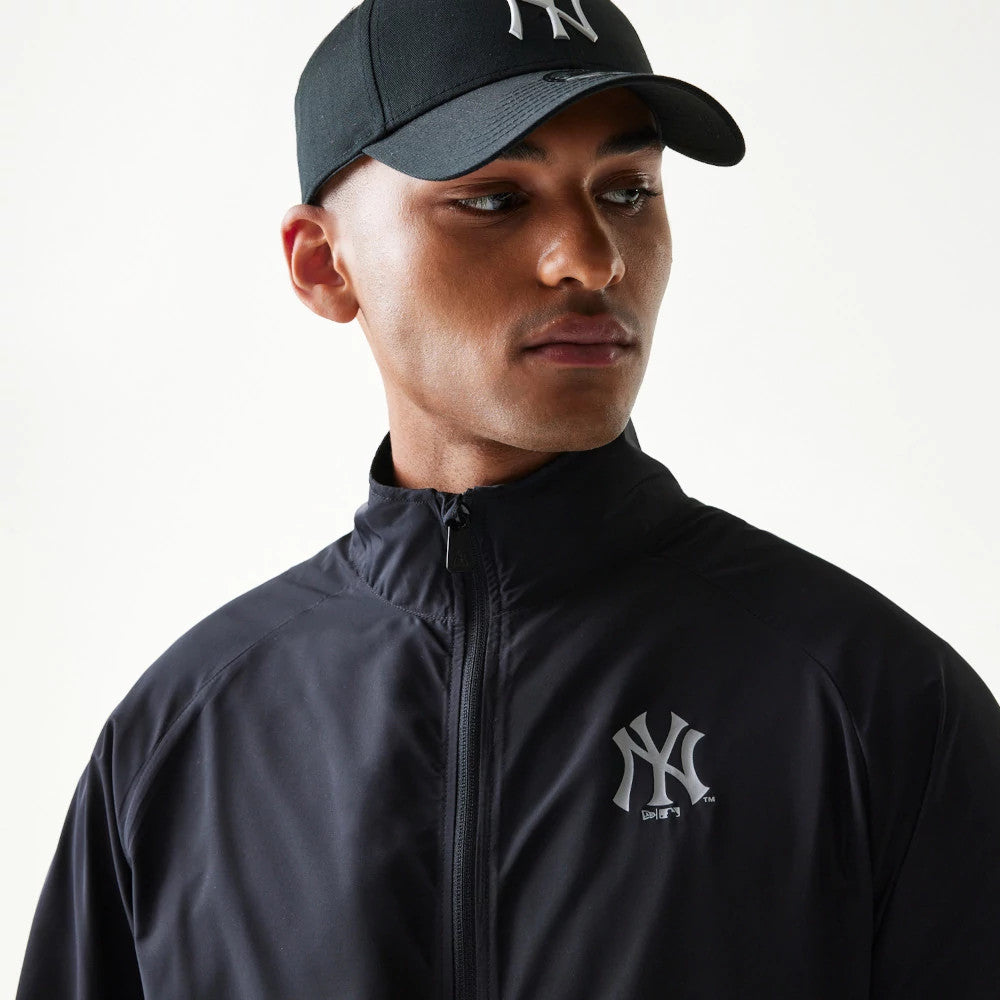 New Era New York Yankees MLB Reflective Strip Black Jacket, front view on-model showing the full-length zip closure and a reflective printed New York Yankees logo on the left chest.