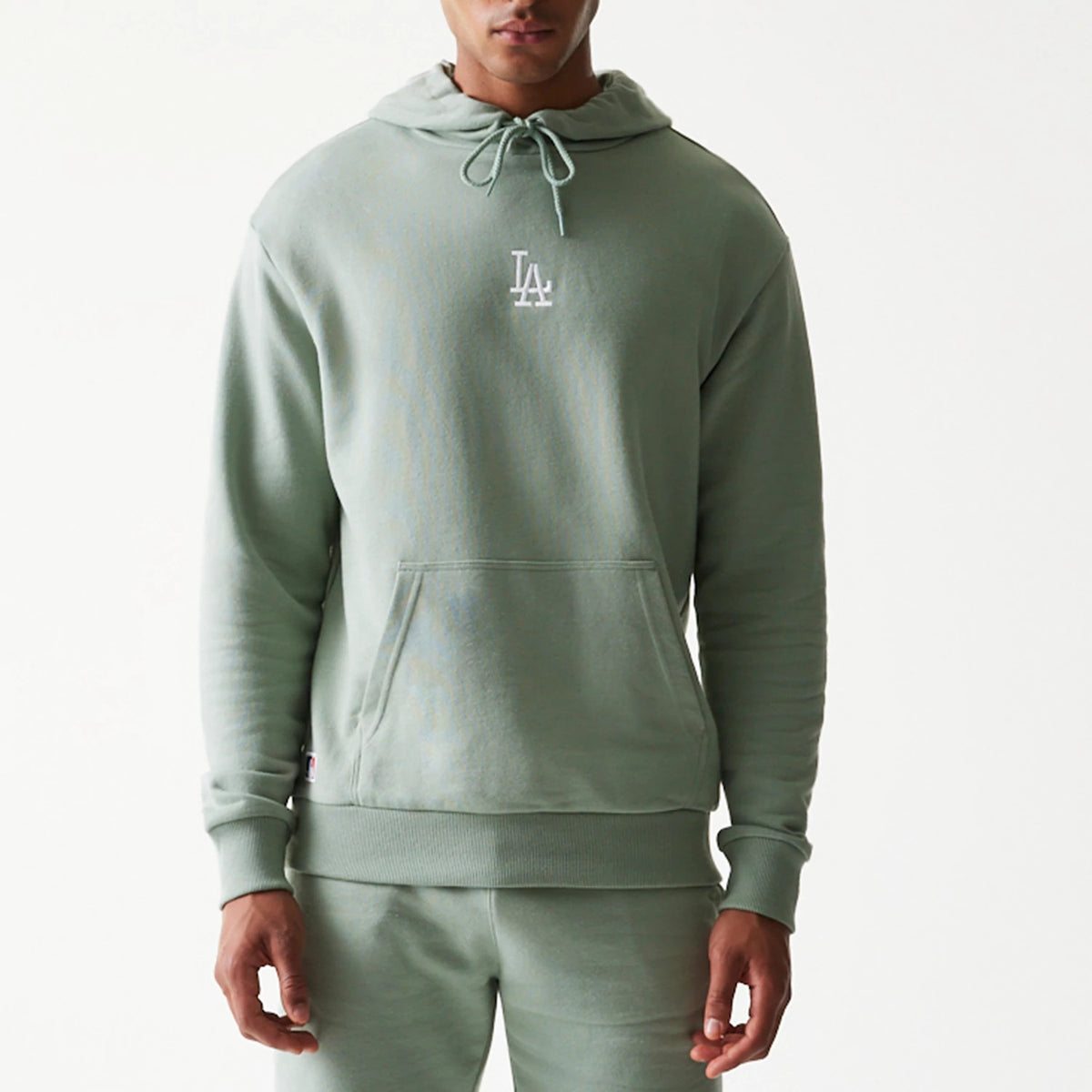 New Era LA Dodgers MLB Midi Green Oversized Pullover Hoodie, front view on-model showing the light green fabric with an embroidered white LA Dodgers logo on the chest, a drawstring hood, and a large front pocket.