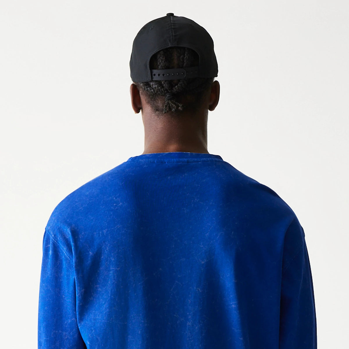 New Era Red Bull Racing Linear Graphic Blue Long Sleeve T-Shirt, back view on-model showcasing the plain rich blue back with long sleeves, paired with a black cap featuring a debossed logo at the rear.