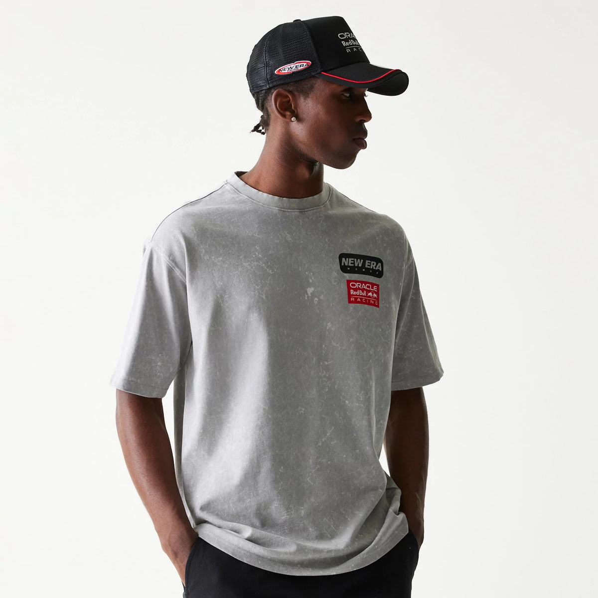New Era Red Bull Racing Linear Graphic Grey Oversized T-Shirt, front view on-model featuring the New Era logo and Red Bull Racing logo printed on the left chest, with a marbled grey pattern throughout and styled with a black cap.