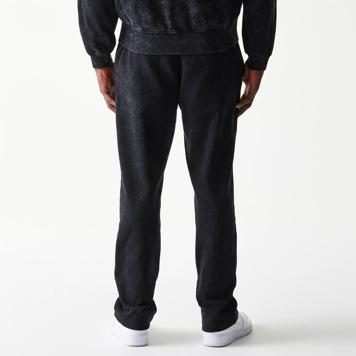 New Era Red Bull Racing Straight Leg Black Straight Leg Joggers, back view on a model showing the casual fit and texture of the black fabric, with elasticated ankle cuffs resting on white trainers.