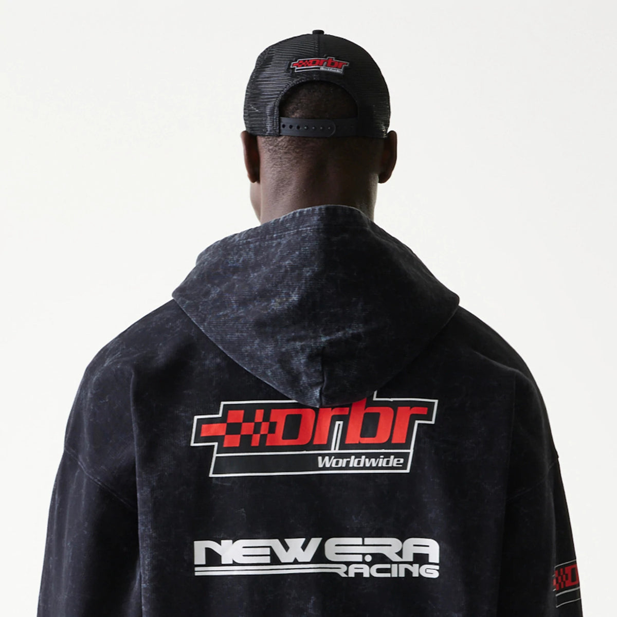 New Era Red Bull Racing Graphic Black Dropped Shoulder Full Zip Hoodie, back view on-model showing red and white orbr branding on the upper back, New Era Racing logo near the waist, and a small graphic on the sleeve.
