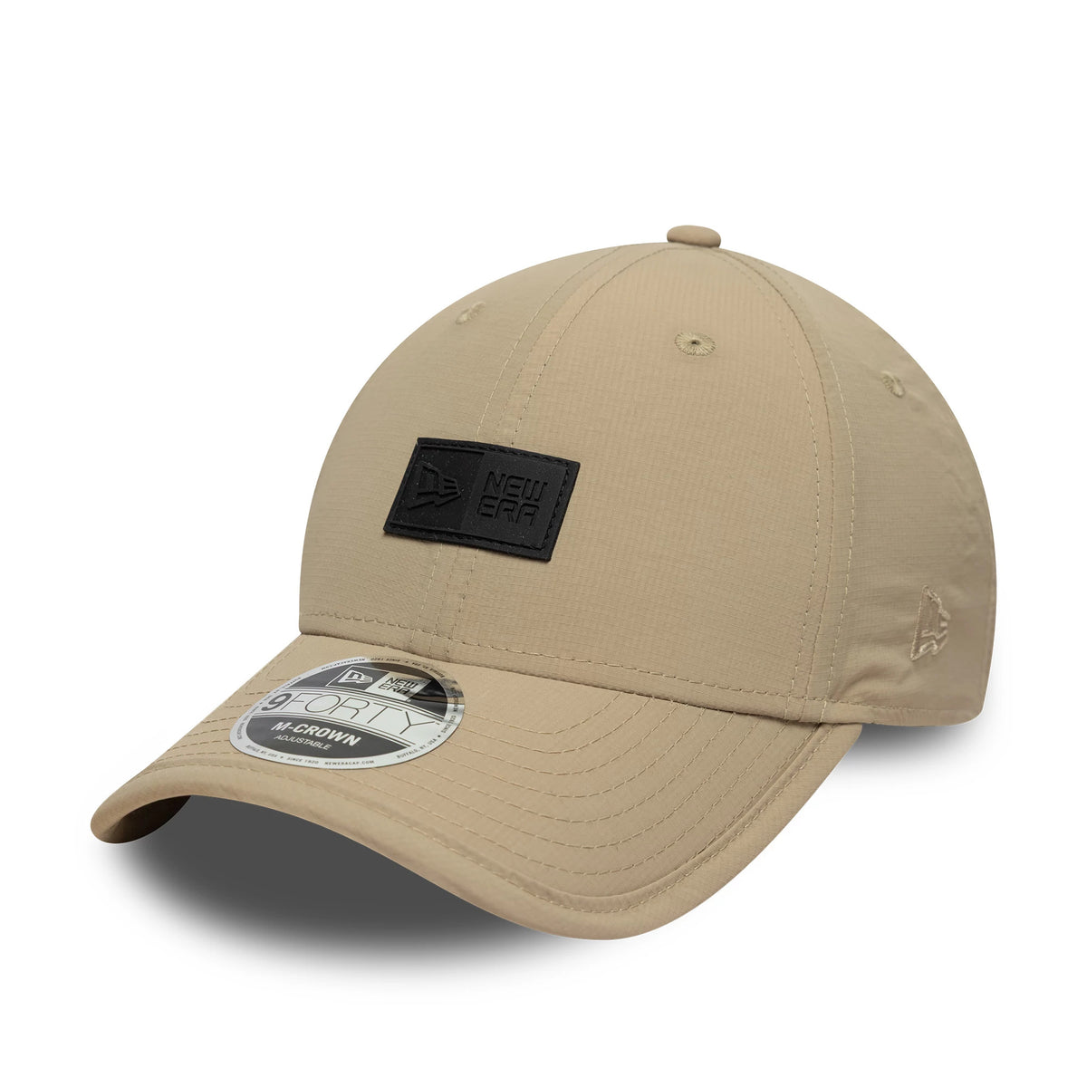 New Era Sport Light Beige 9FORTY M-Crown Cap, three-quarter view showing a black New Era patch on the front panel, curved visor with a 9FORTY size sticker, and the New Era flag logo embroidered on the left side.