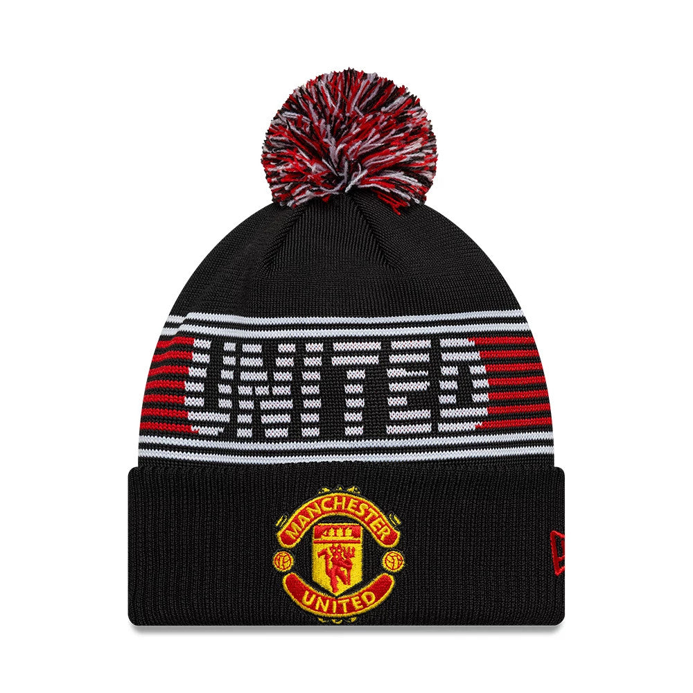 New Era Manchester United FC Black Bobble Knit Beanie Hat, front view showing the embroidered Manchester United crest on the cuff, red and white stripe with UNITED text across the crown, and a red and black mixed pom on top.