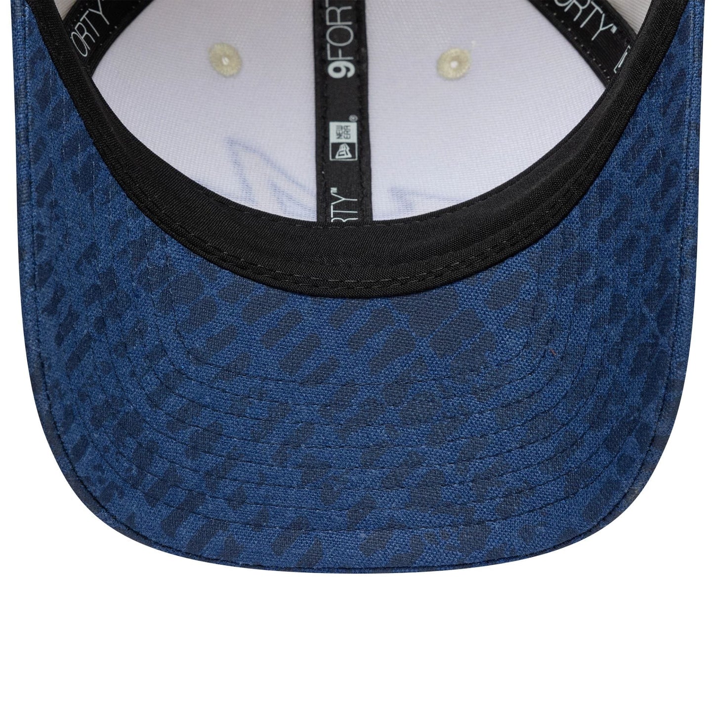 Alpine Racing Heritage Cream & Dark Blue New Era 9FORTY M-Crown Cap, inside view showing the black sweatband with repeated 9FORTY branding, cream crown taping, and a round A logo sticker on the underside of the dark blue visor.