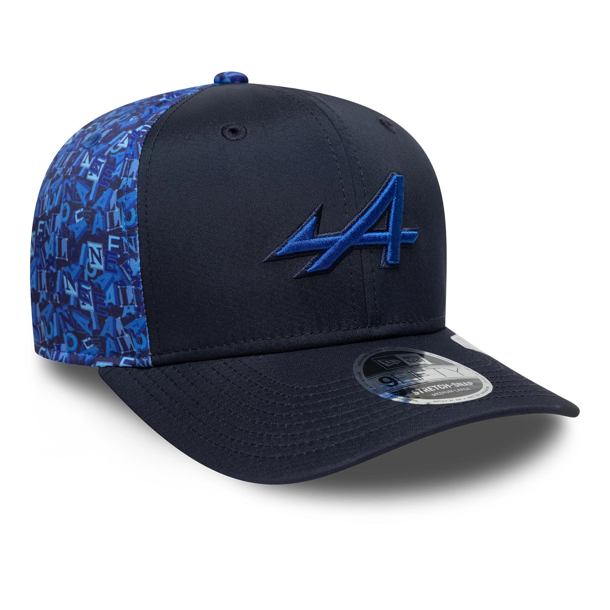 Alpine Racing All Over Print Navy New Era 9FIFTY Stretch Snap Cap, three-quarter view showing a blue embroidered A logo on the front panel, dark navy visor with 9FIFTY size sticker, and patterned side panels with Alpine motifs.