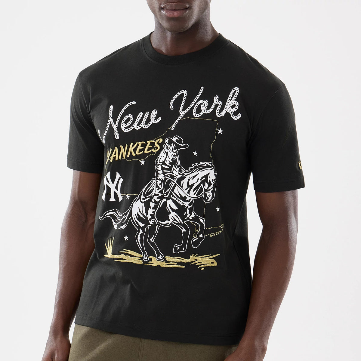 New Era New York Yankees MLB Cowboy Graphic Black T-Shirt, front view on-model showing a large cowboy and horse graphic with New York Yankees lettering across the chest and an embroidered New Era logo on the sleeve.