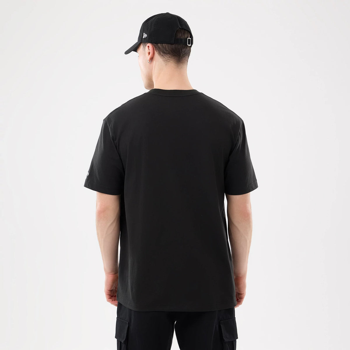 New Era New York Yankees MLB Script Graphic Black T-Shirt, back view on a model wearing a black cap, showing the plain black back with short sleeves, and part of an embroidered New Era logo on the left sleeve.