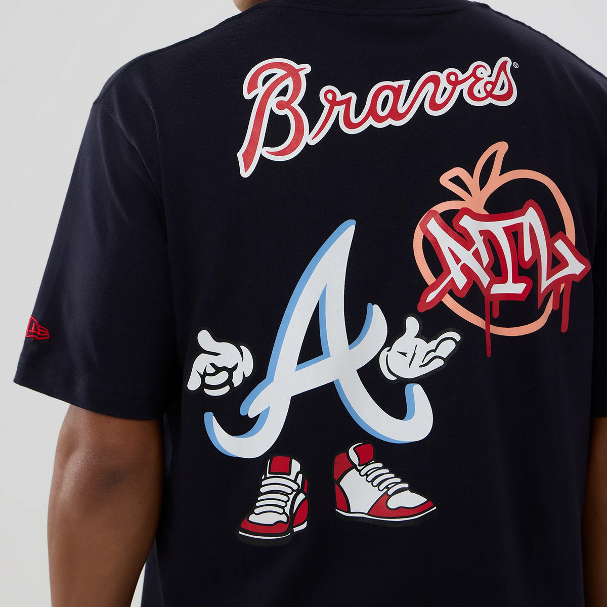 New Era Atlanta Braves MLB Graphic Navy T-Shirt, back view showing large animated A graphic with hands and sneakers, red Braves script above, and peach design with ATL lettering, worn by a model.