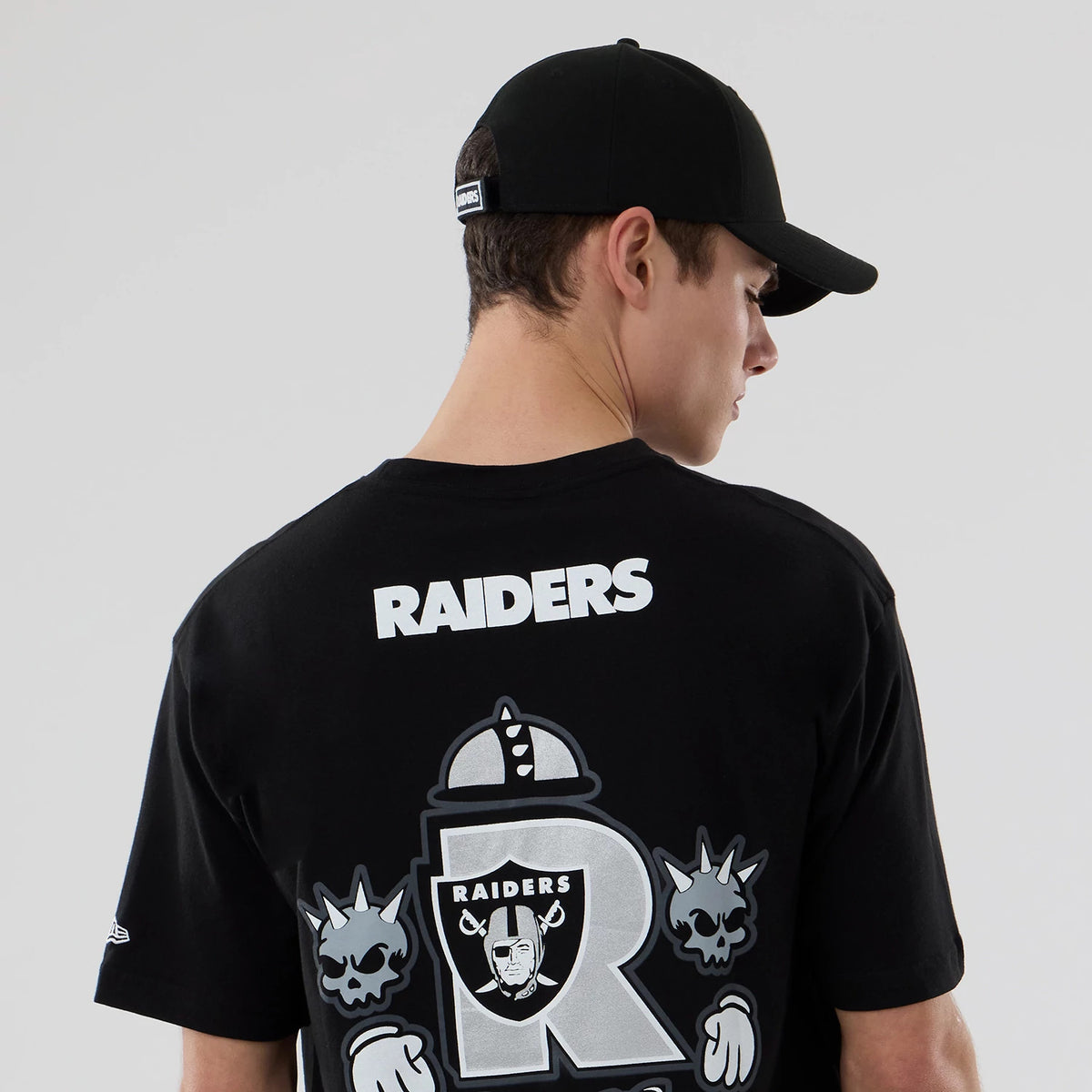 New Era Las Vegas Raiders NFL Graphic Black T-Shirt, back view on-model featuring white Raiders lettering across the upper back and a large graphic design incorporating the Raiders logo and additional artwork on the lower back.