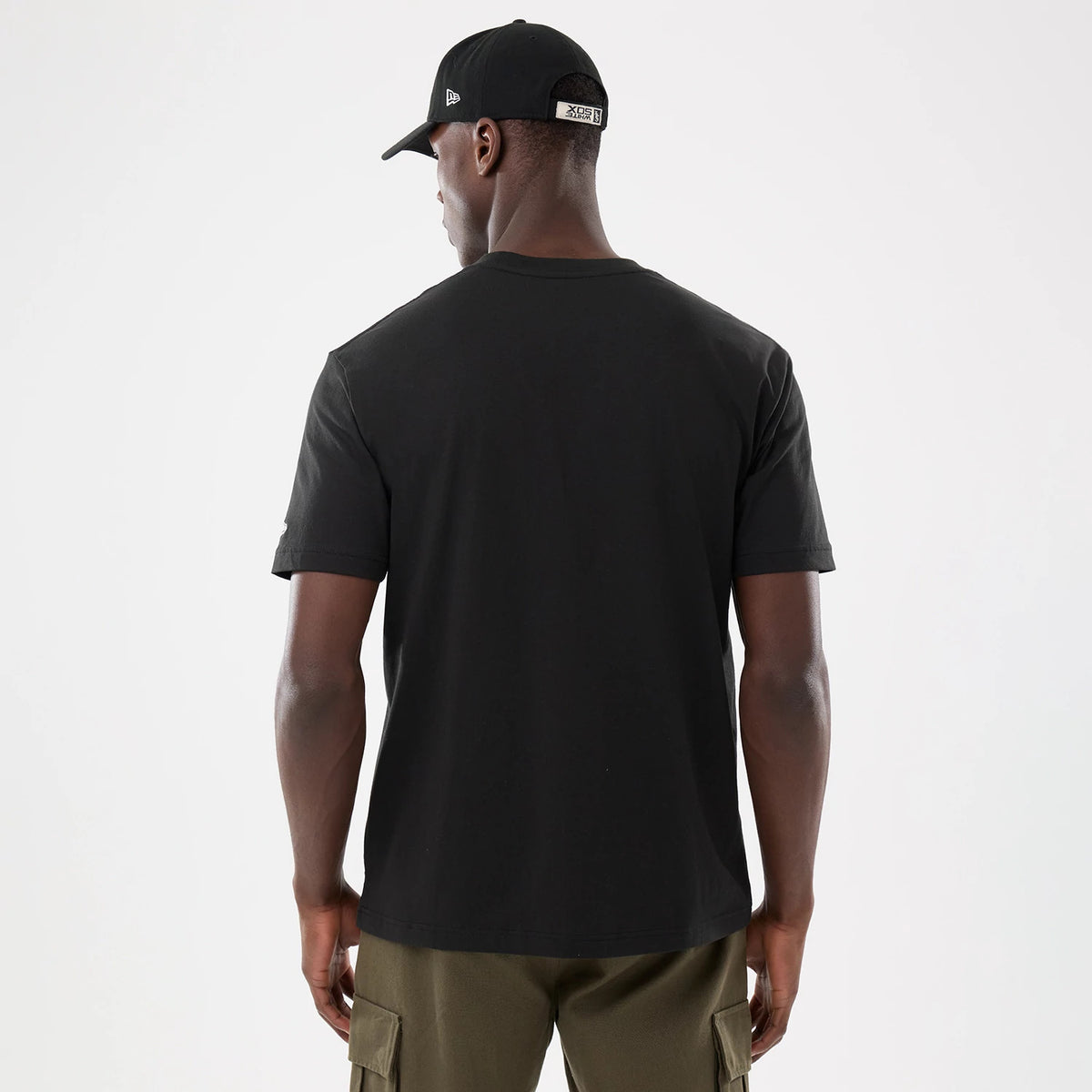 New Era Chicago White Sox MLB Script Graphic Black T-Shirt, back view on-model highlighting the plain black of the t-shirt, paired with a black cap featuring a raised New Era logo on the side and a badge above the back strap.
