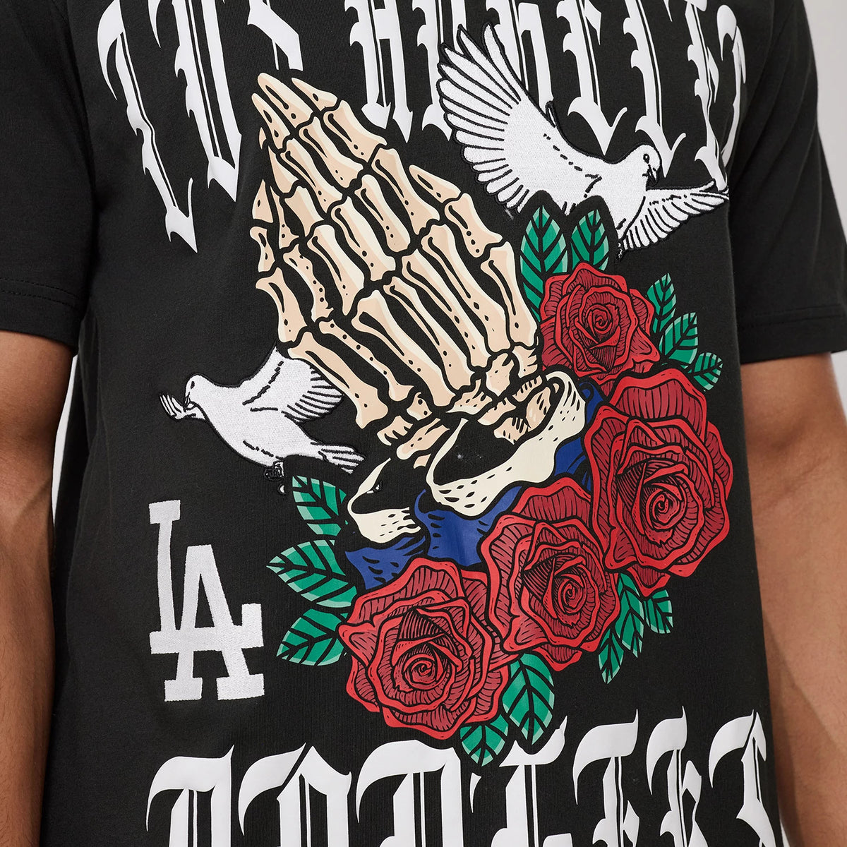 New Era LA Dodgers MLB Script Graphic Black T-Shirt, front view showcasing a detailed graphic of a skeletal hand surrounded by red roses, two white doves, and an embroidered LA logo on the black fabric.