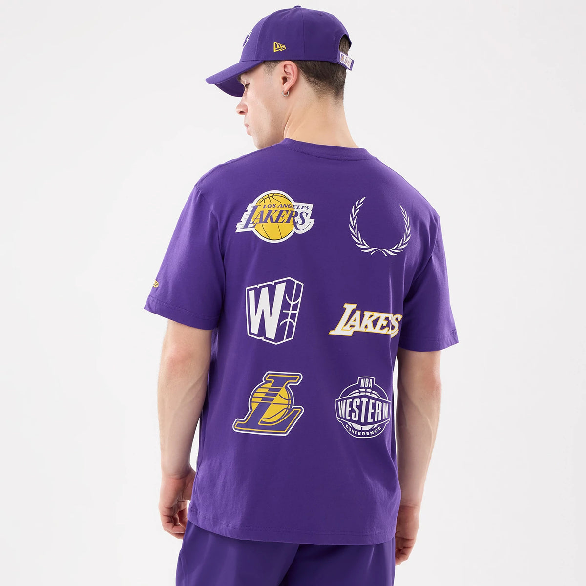 New Era LA Lakers NBA Match Purple T-Shirt, back view on-model highlighting multiple printed logos and graphics including the LA Lakers emblem, NBA Western Conference logo, and additional team symbols across the purple fabric.