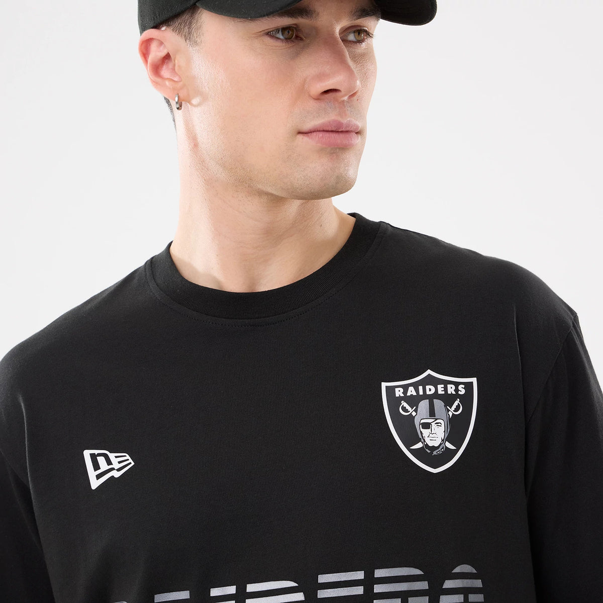 New Era Las Vegas Raiders NFL Match Black T-Shirt, front view on-model showing a white printed Raiders shield logo on the left chest and a white printed New Era flag logo on the right chest.