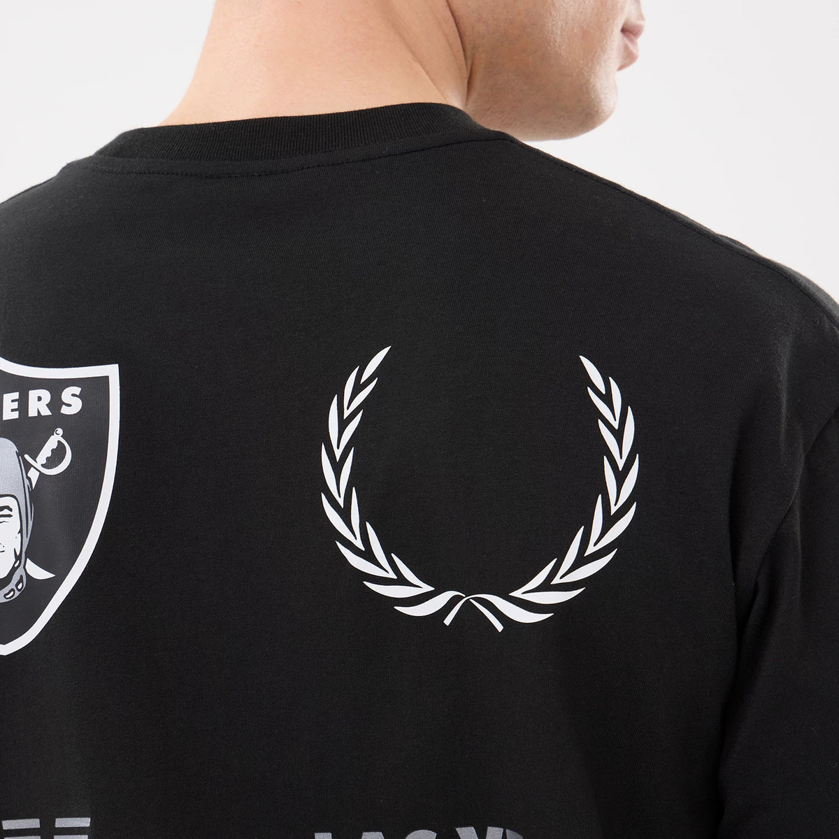 New Era Las Vegas Raiders NFL Match Black T-Shirt, back view showing the white printed laurel wreath and part of the Raiders logo on the upper back, worn by a model with a close-cut hairstyle.