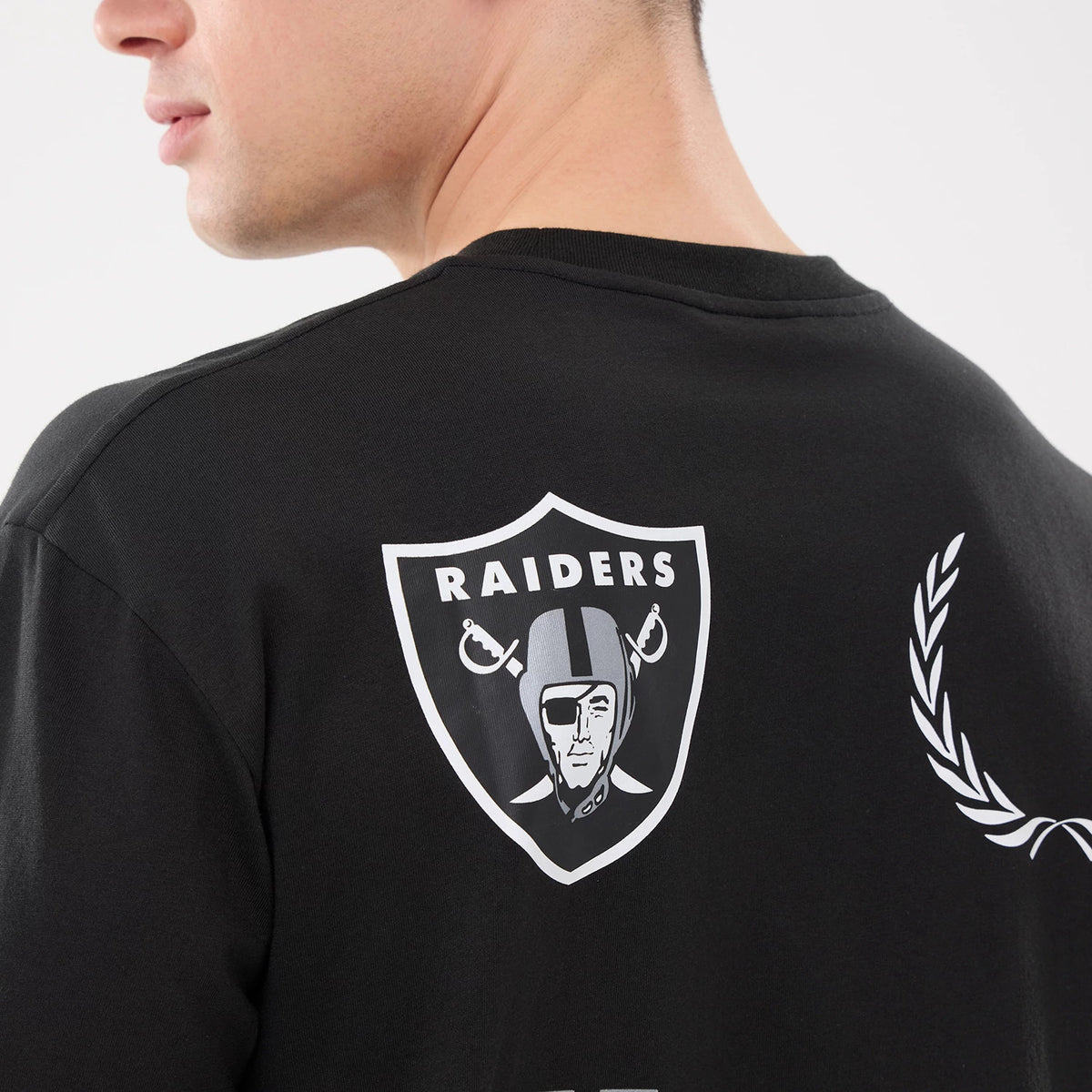 New Era Las Vegas Raiders NFL Match Black T-Shirt, back view showing the large printed Raiders logo centred across the upper back, with a view of laurel graphics to the side, styled casually on a model.