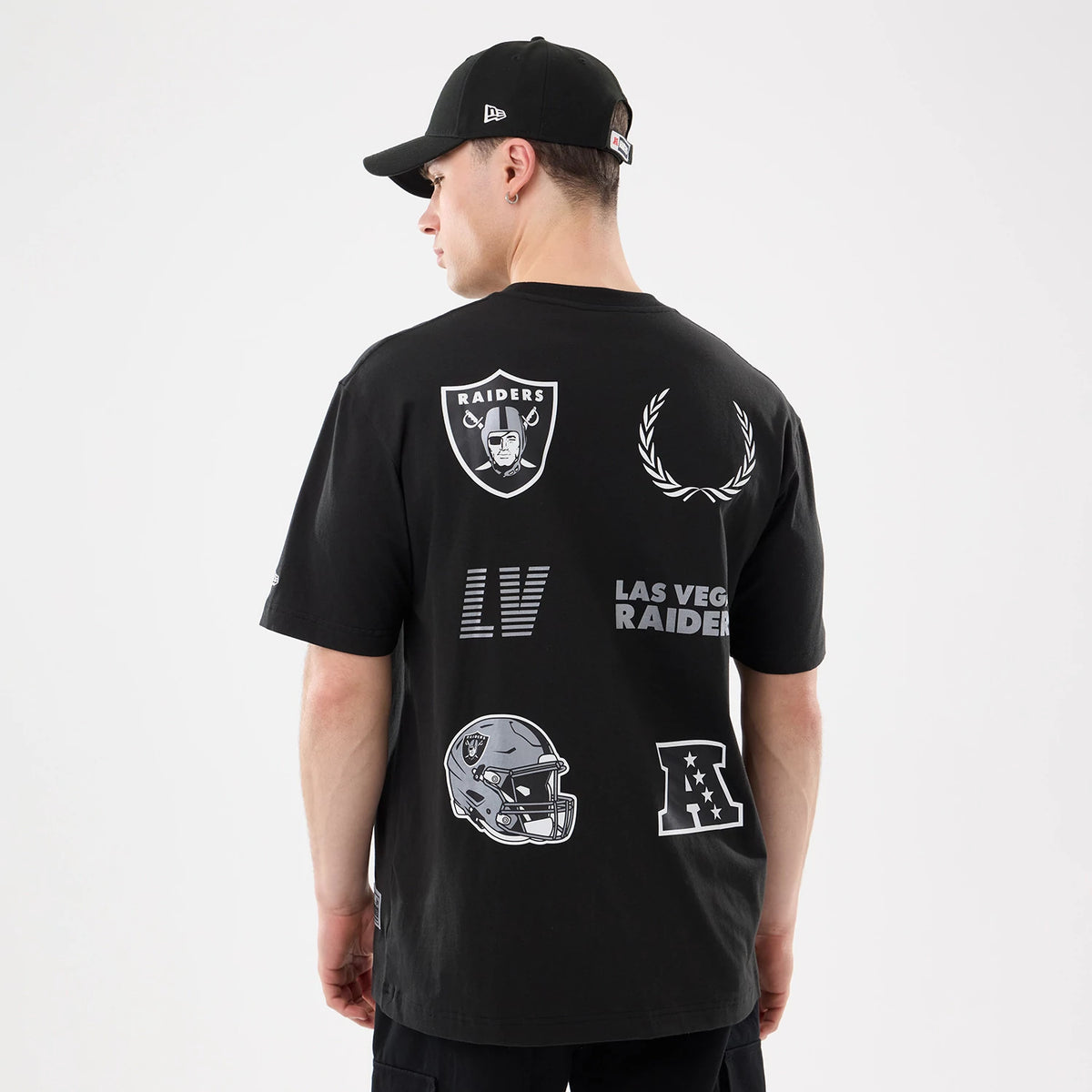 New Era Las Vegas Raiders NFL Match Black T-Shirt, back view showing large printed graphics including the Raiders shield logo, football helmet, laurels, LV lettering and AFC emblem, worn by a model with a matching black cap.