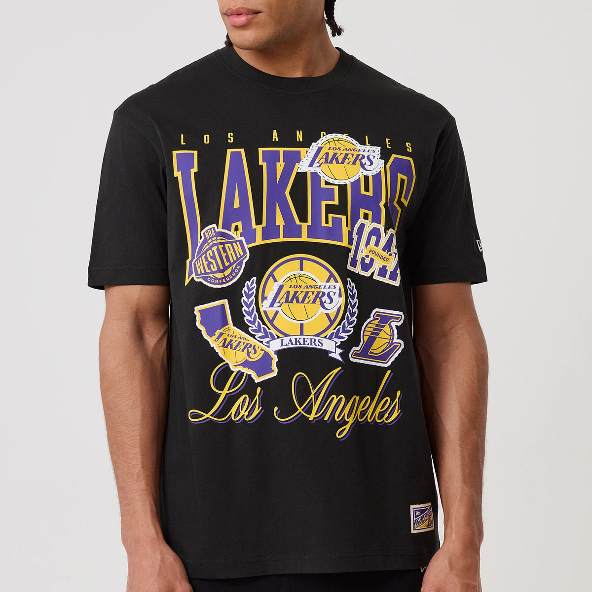New Era LA Lakers NBA Sport Classic Black T-Shirt, front view on-model highlighting the large Lakers and Los Angeles graphics in yellow and purple across the chest, with multiple basketball-themed logos and an embroidered New Era logo on the sleeve.