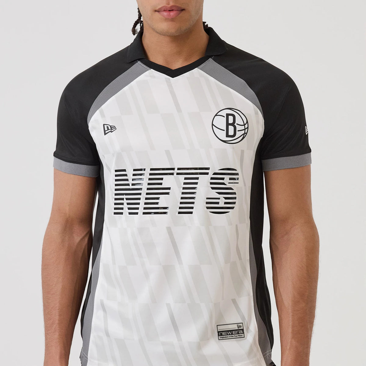 New Era Brooklyn Nets NBA Match Black T-Shirt, front view on a model featuring a large NETS graphic across the chest, a black and white basketball logo to the upper right, and an embroidered New Era logo on the left sleeve.