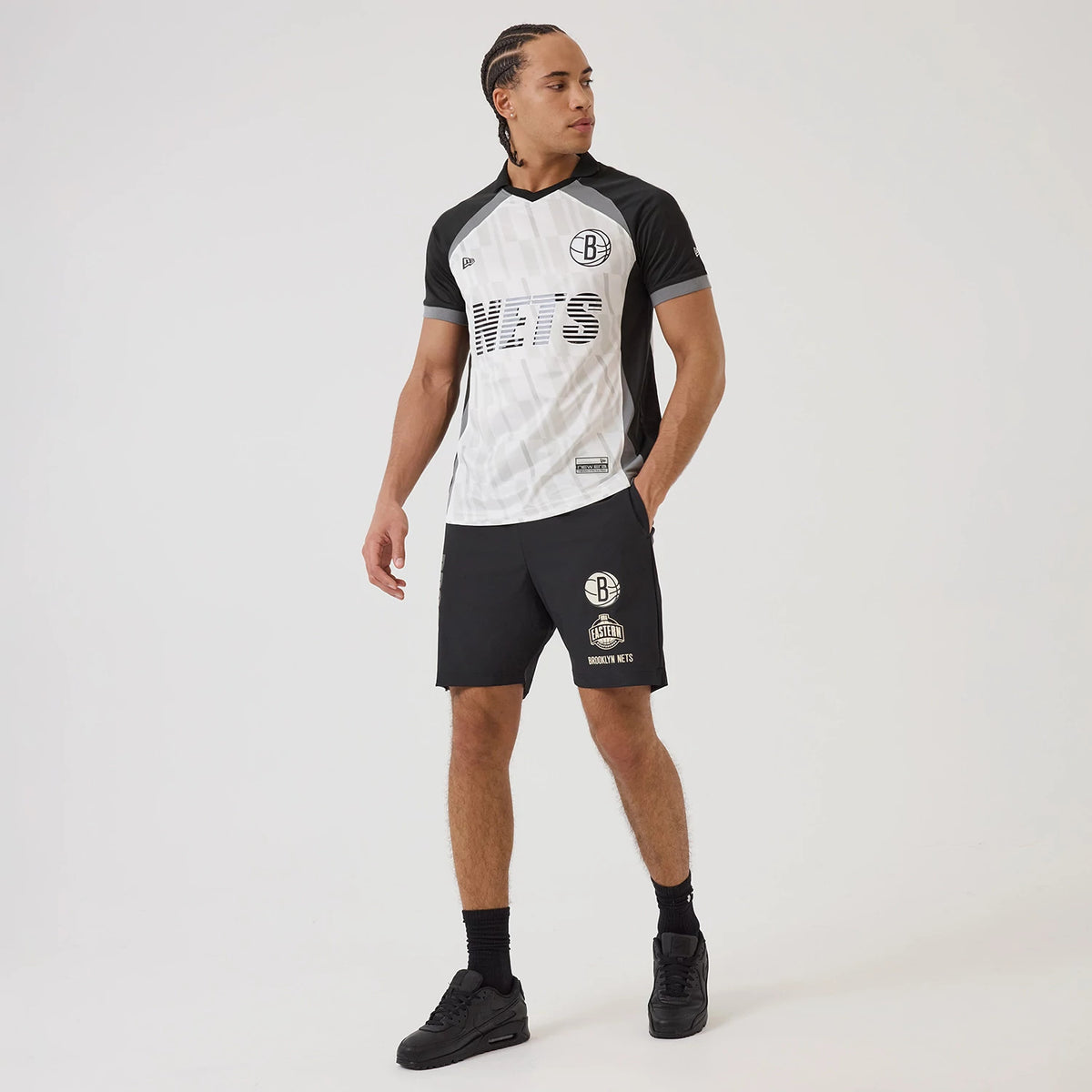 New Era Brooklyn Nets NBA Match Black T-Shirt, front view on-model displaying the black and white design with an embroidered Nets logo on the left chest, striped lettering across the front, and contrasting black sleeves.