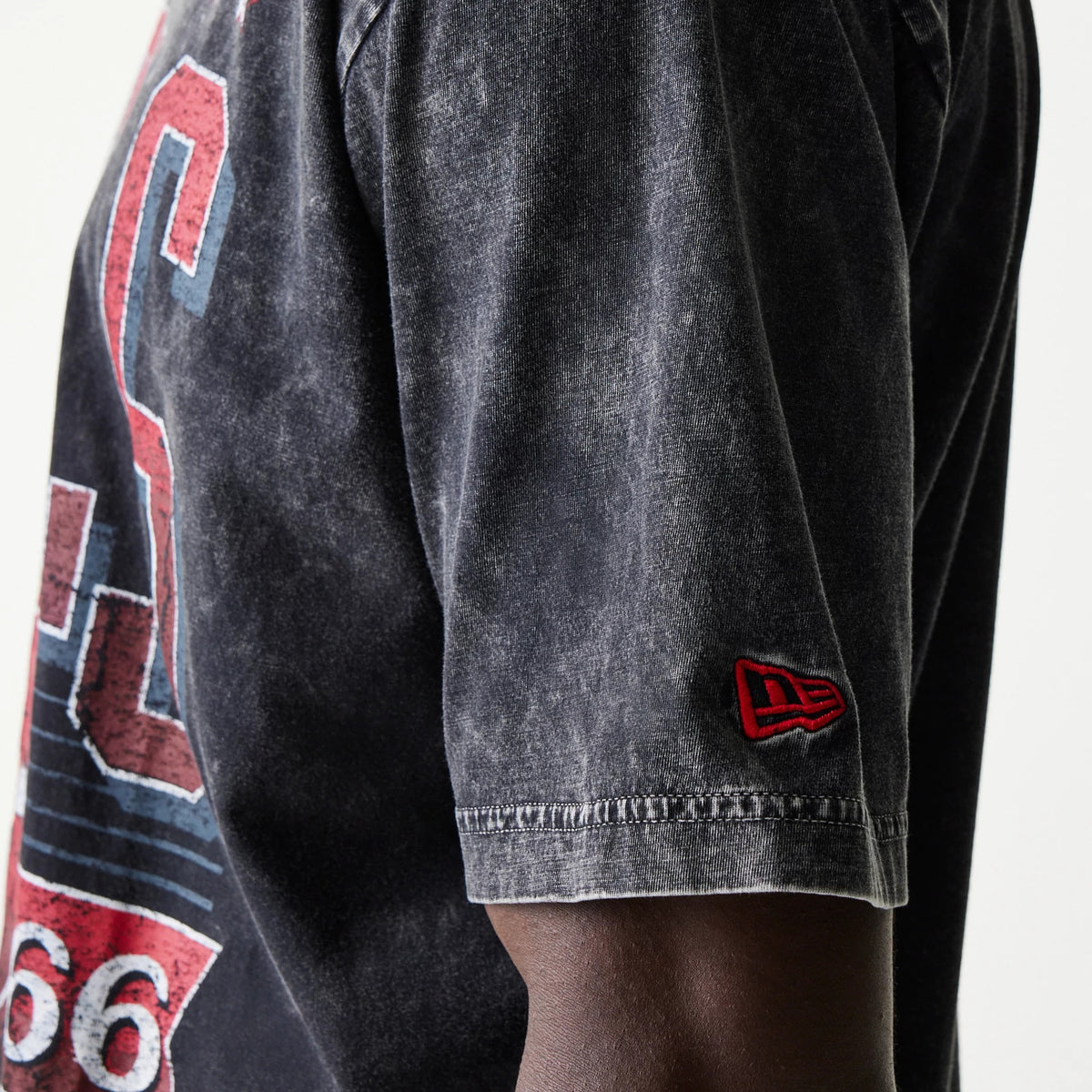 New Era Chicago Bulls NBA Black T-Shirt, side view showing a faded black fabric with the red and blue Bulls graphic on the chest and a red embroidered New Era logo on the sleeve hem near the shoulder.