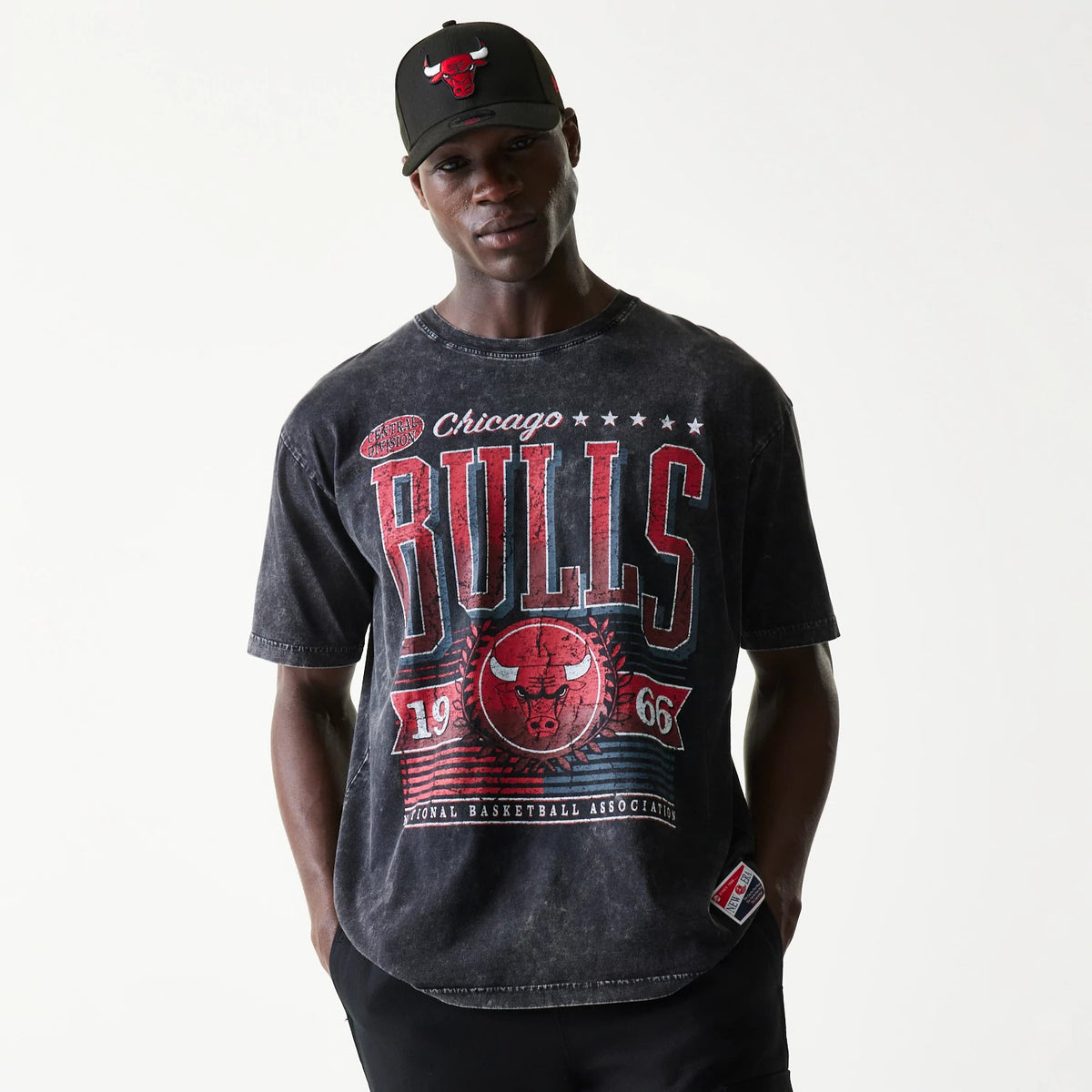New Era Chicago Bulls NBA Black T-Shirt, front view on-model showing a large distressed red Bulls graphic with stars and 1966 across the chest, paired with a black cap featuring an embroidered Bulls logo at the centre front.