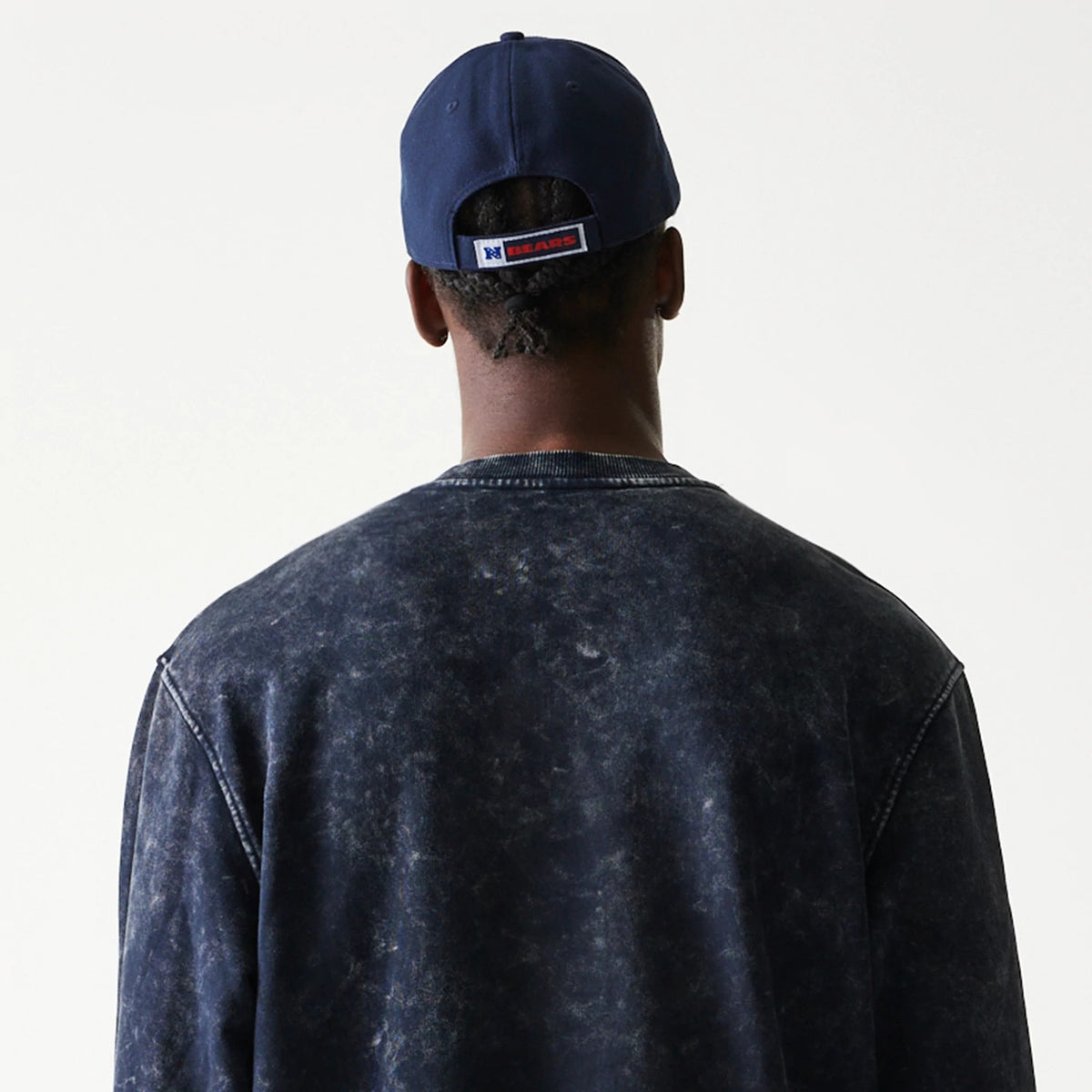 New Era Chicago Bears NFL Navy Crew Neck Sweater, rear view on a model wearing a matching navy cap, showing the washed navy fabric and ribbed neck detail with stitching along the shoulders.