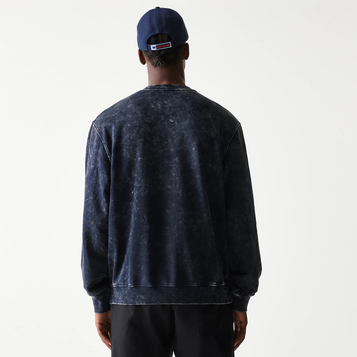 New Era Chicago Bears NFL Navy Crew Neck Sweater, back view on-model showing the washed navy fabric with marbling effect and ribbed cuffs, worn with a blue cap showing an embroidered logo at the back.
