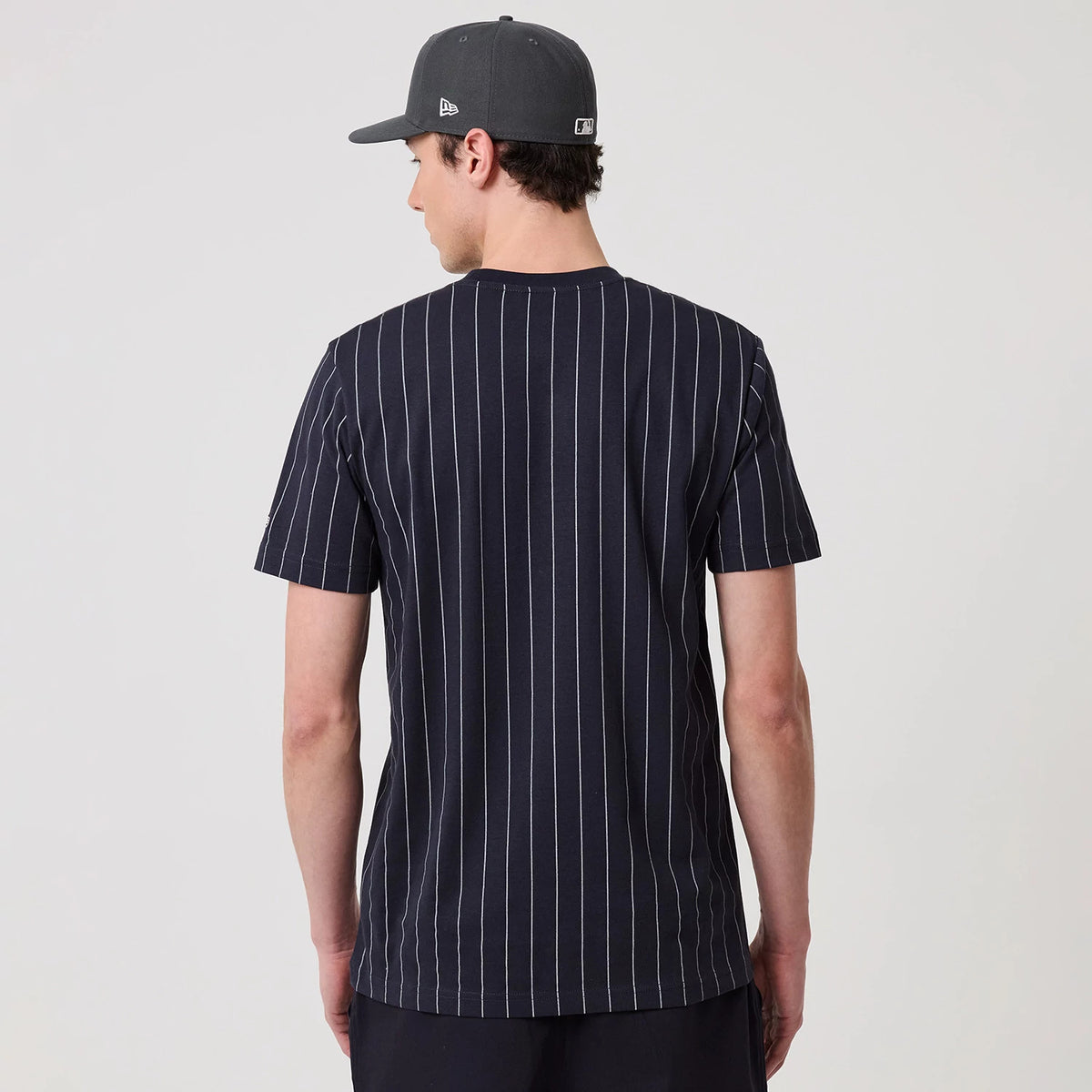New Era New York Yankees MLB Pinstripe Navy T-Shirt, back view on a model showing thin white vertical pinstripes across the navy fabric, with short sleeves and a simple crew neck style.
