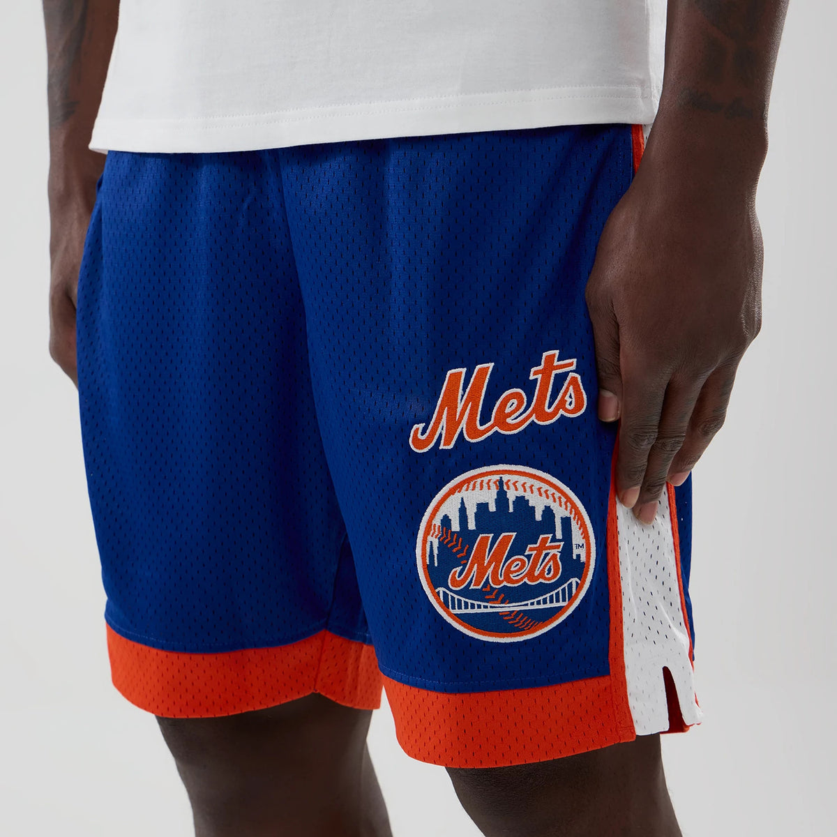 New Era New York Mets MLB Blue Mesh Shorts, front view featuring orange Mets lettering and logo on the left leg, with contrasting white side stripes and an orange hem accent on the blue mesh fabric.