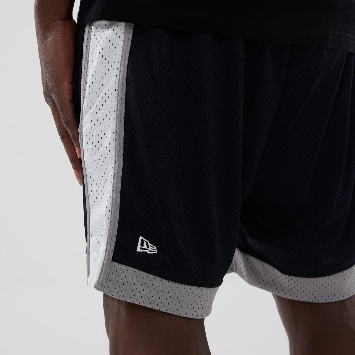 New Era New York Yankees MLB Navy Mesh Shorts, side view showing navy mesh fabric with white side panels and grey trim, featuring an embroidered New Era logo near the hem, worn by a model.