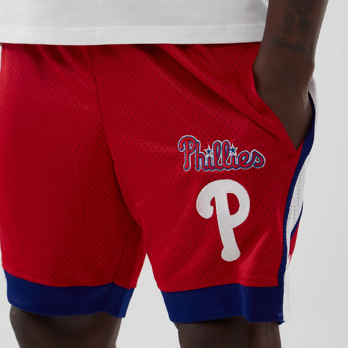 New Era Philadelphia Phillies MLB Red Mesh Shorts, front view showing the white embroidered P logo below the waistband, Phillies script in blue and white on the right leg and blue trim at the hem.