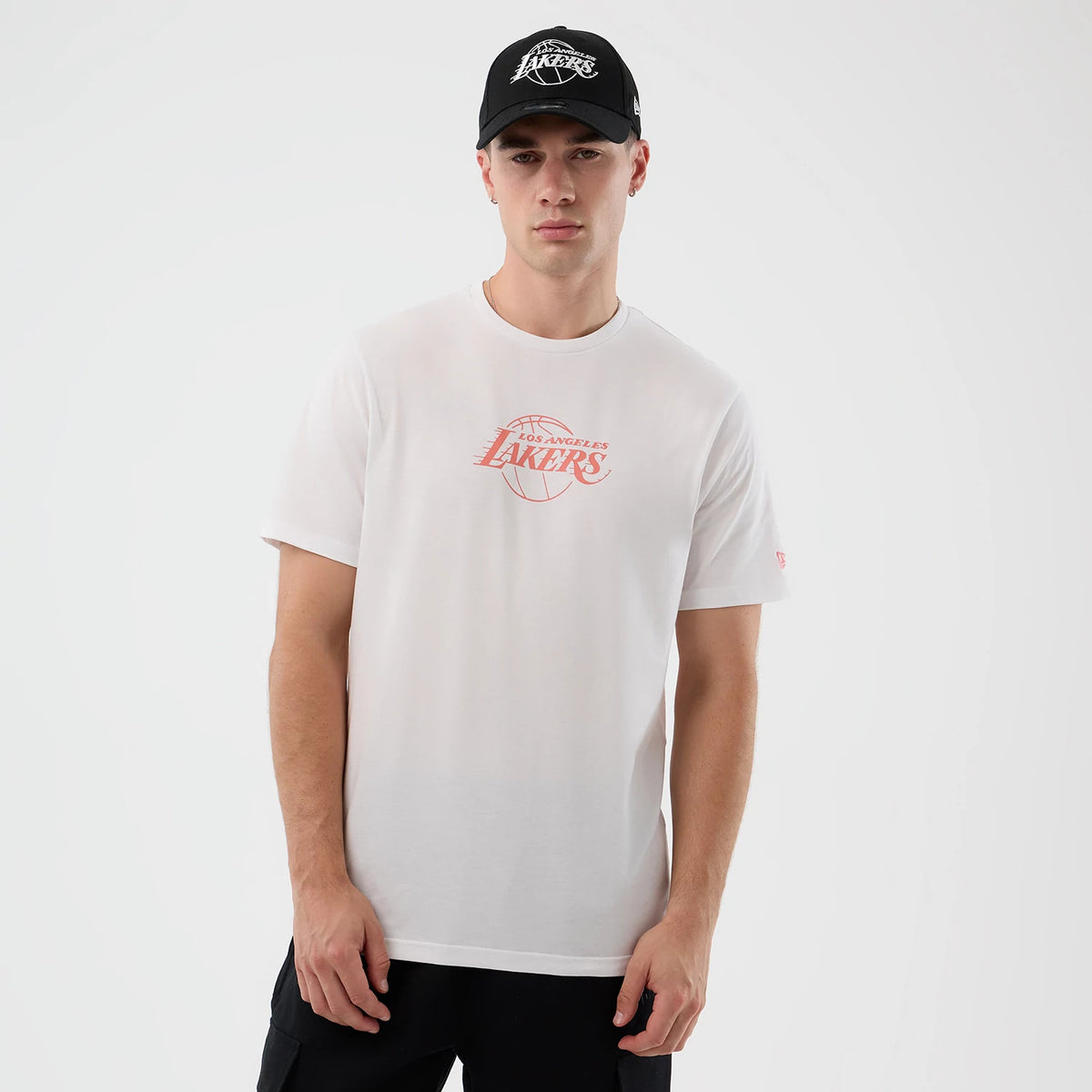 New Era LA Lakers NBA Back To School Graphic White T-Shirt, front view on a model paired with a black Lakers cap, featuring a red Lakers basketball graphic centred on the chest and an embroidered New Era flag on the left sleeve.