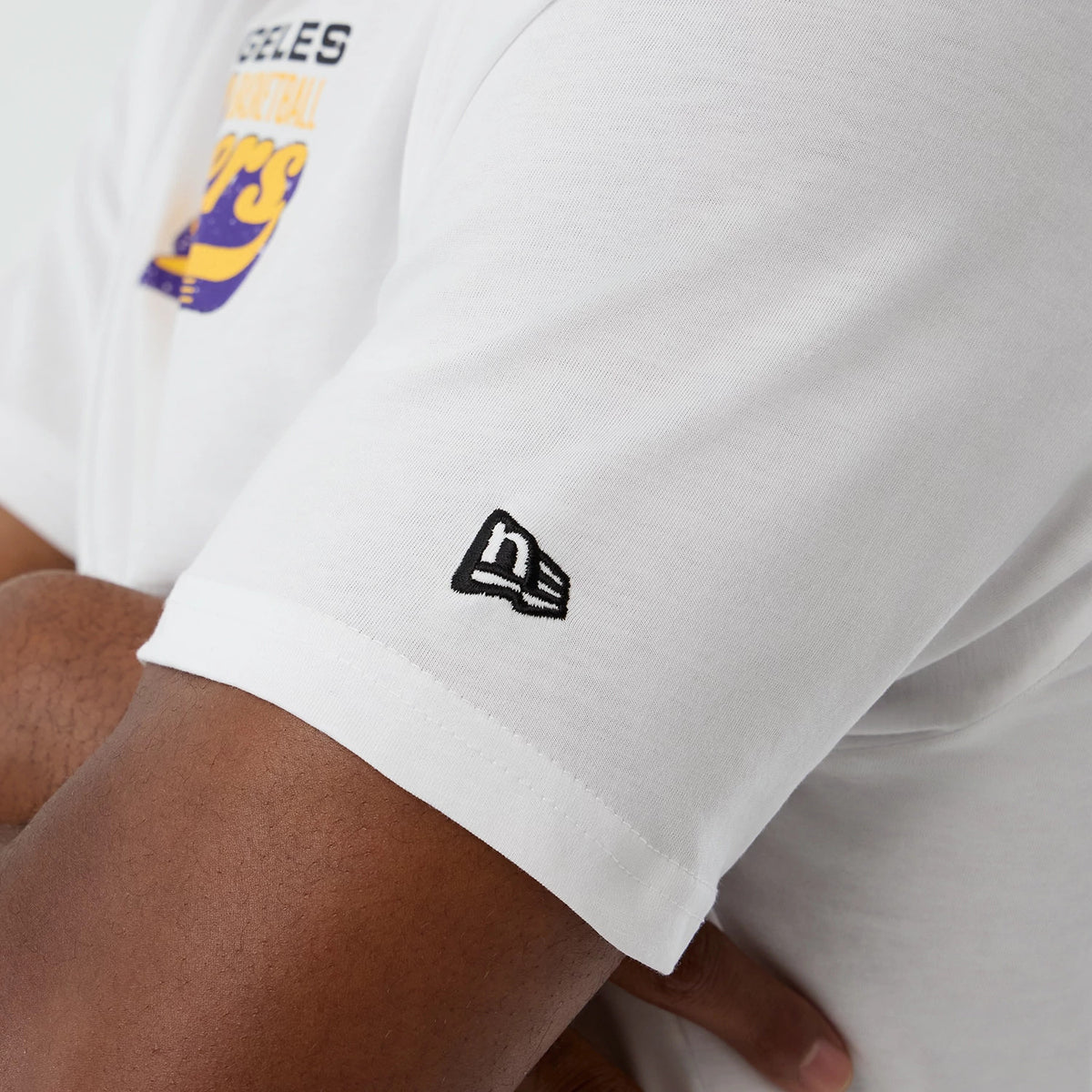 New Era LA Lakers NBA Script Back To School White T-Shirt, three-quarter view showing a person wearing the shirt with a black embroidered New Era logo on the sleeve and the Los Angeles Lakers graphic partially on the chest.