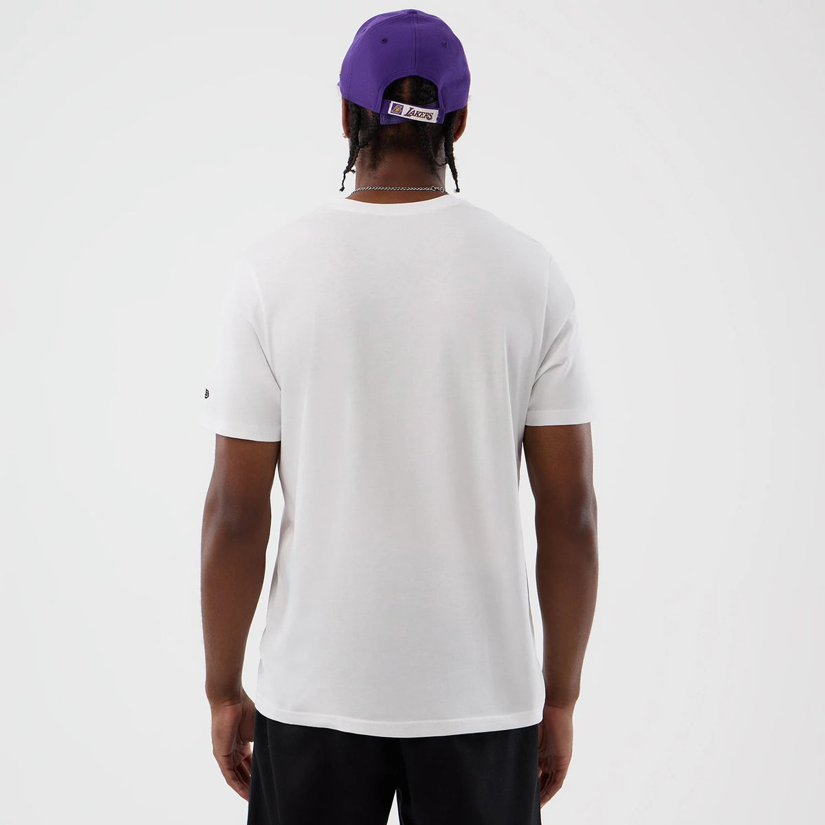 New Era LA Lakers NBA Script Back To School White T-Shirt, back view on a model with a purple cap, showcasing a plain white back with a small embroidered New Era logo on the sleeve and a woven Lakers label on the cap.