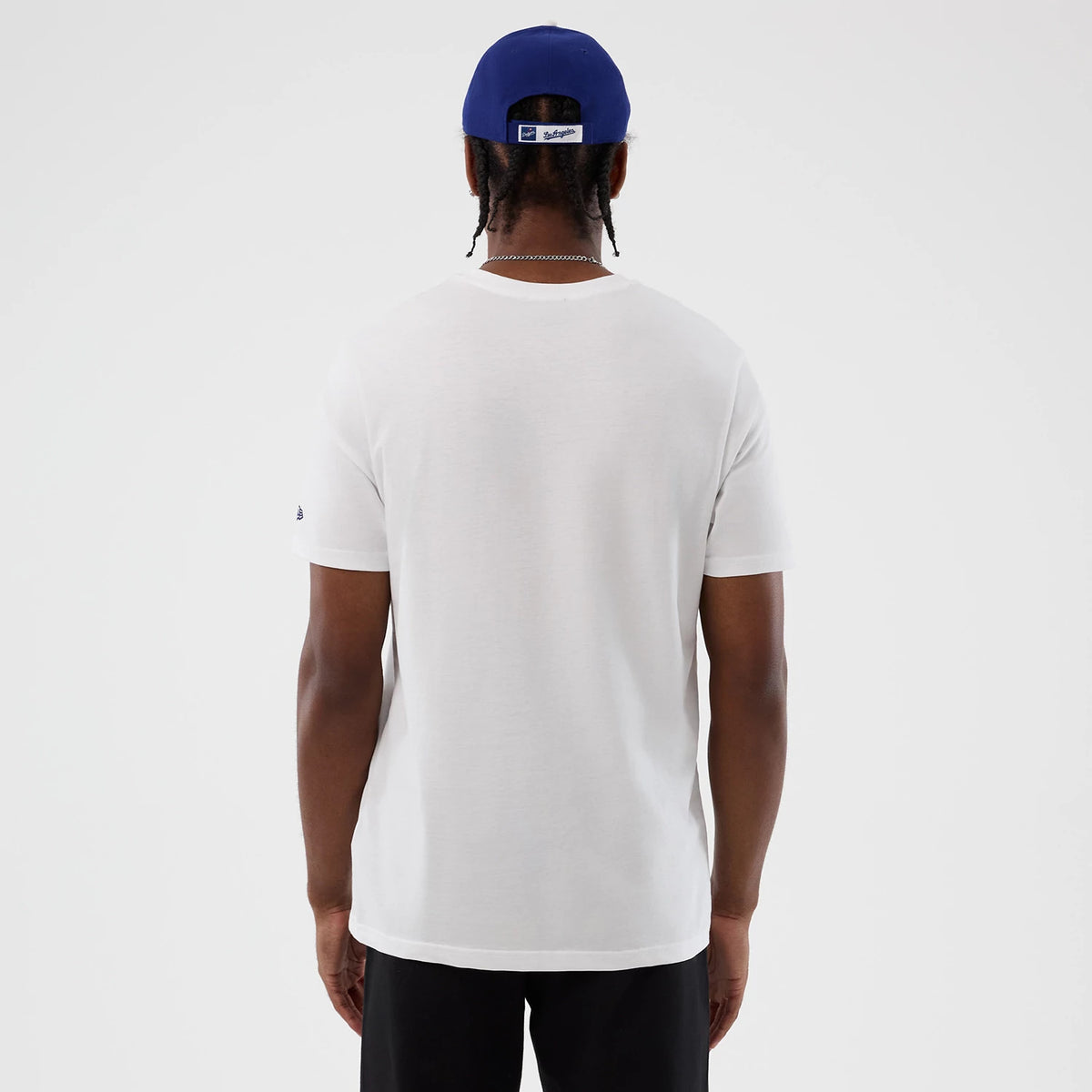 New Era LA Dodgers MLB Back To School White T-Shirt, back view showing the plain white rear without graphics, short sleeves with a small embroidered New Era logo on the left sleeve, paired with a blue cap from the back.