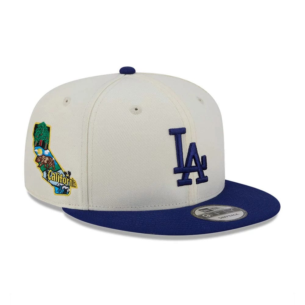 LA Dodgers MLB Localized White New Era 9FIFTY Snapback Adjustable Cap, three-quarter view showing the blue embroidered LA logo on the front panel, a colourful California graphic on the right side, and a white 9FIFTY size sticker on the blue visor.