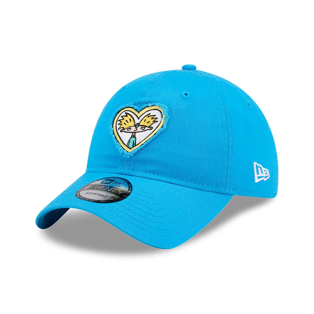 Hey Arnold Heart Blue New Era 9TWENTY Adjustable Cap, three-quarter view showing a yellow and black embroidered heart-shaped Arnold graphic on the front, with a curved visor and a black 9TWENTY size sticker.