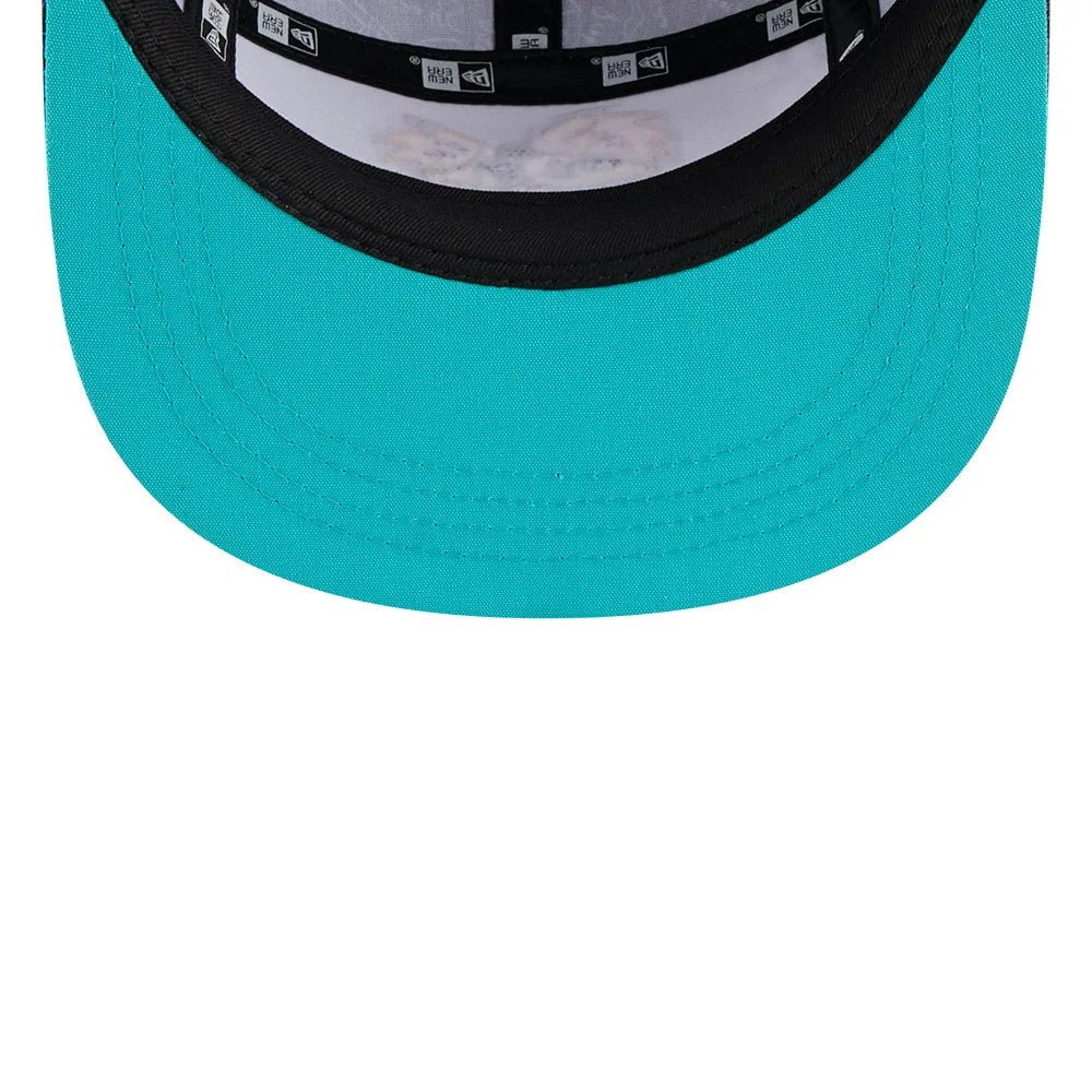 New Era Hey Arnold All Over Print Black Camper Cap, inside view showing the black taping with white New Era logos, a black sweatband and a bright turquoise undervisor with neat stitching along the edge.