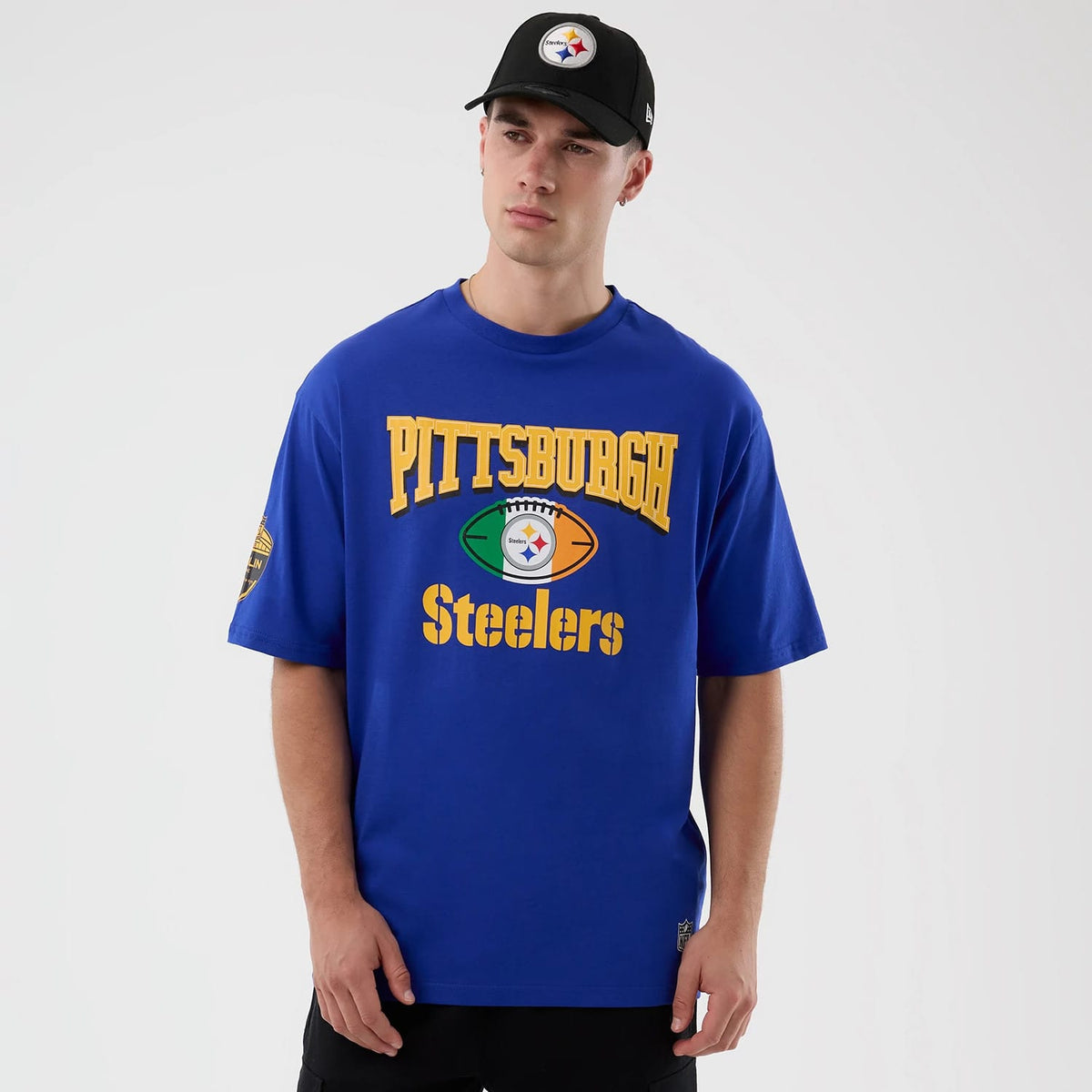 New Era Pittsburgh Steelers NFL International Series Games Blue Oversized T-Shirt, front view on-model featuring a large printed Pittsburgh Steelers logo and lettering across the chest with additional logo on the left sleeve.