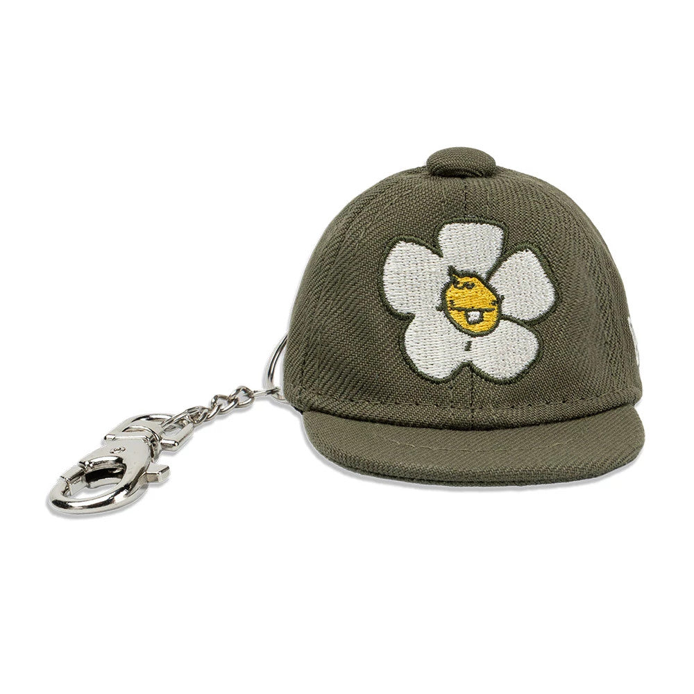 New Era x Rodrigo Roji Flower Green Mini 59FIFTY Fitted Cap, front view showing a white flower with a yellow centre embroidered on the structured green crown and a silver keychain attached to the rear.