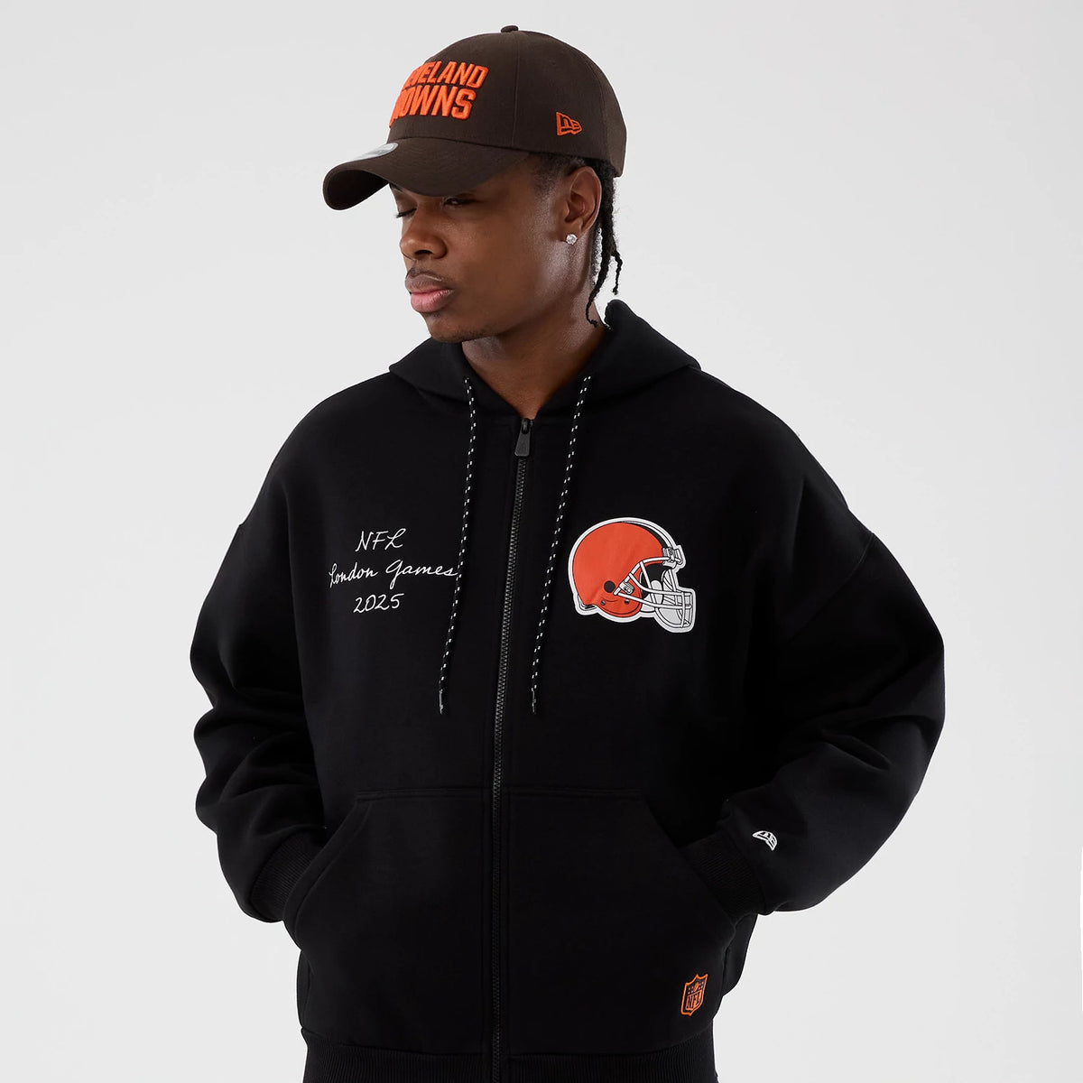 New Era Cleveland Browns NFL International Series Games Black Full Zip Hoodie, front view on-model showing a large embroidered team logo on the right chest, white lettering on the left, and a small embroidered New Era logo on the left sleeve.