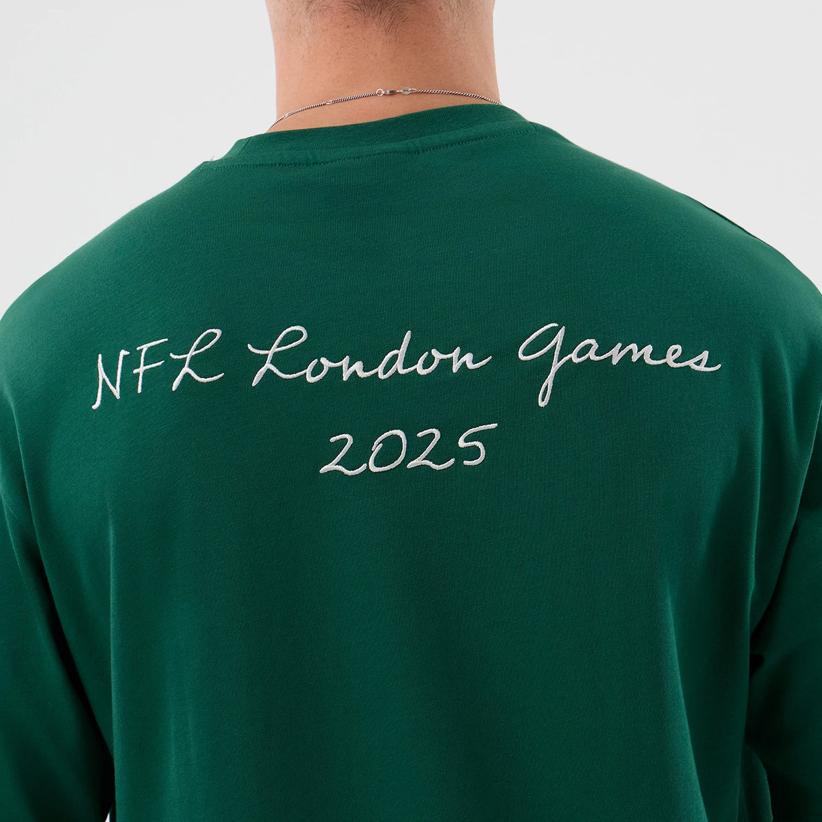 New Era New York Jets NFL International Series Games Green Oversized T-Shirt, back view showing the white embroidered text NFL London Games 2025 across the upper back, worn by a model with a simple chain necklace.