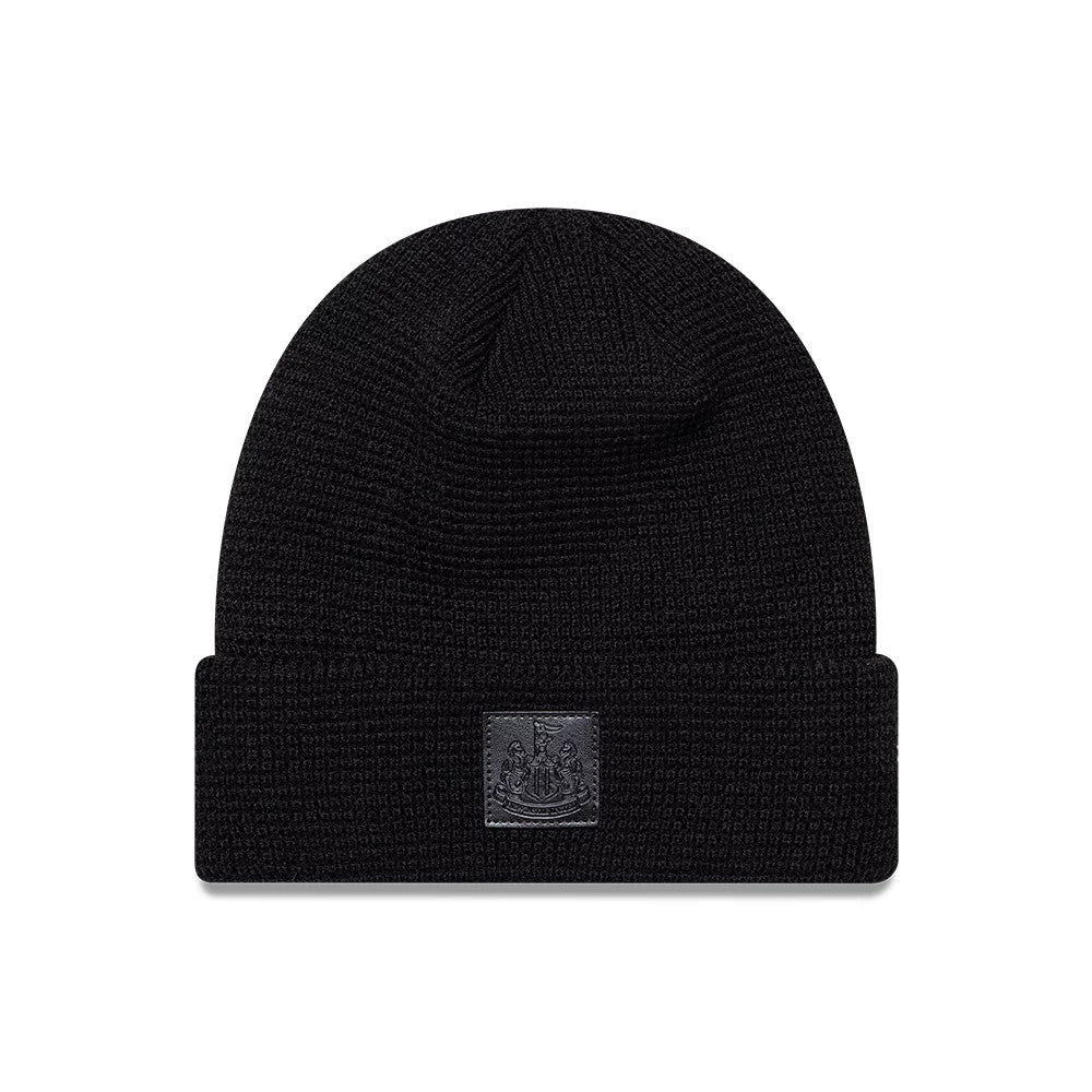 New Era Newcastle United FC Waffle Black Cuff knit Beanie Hat, front view showing the black embossed Newcastle United crest on the folded cuff, with a textured waffle knit pattern covering the entire beanie.