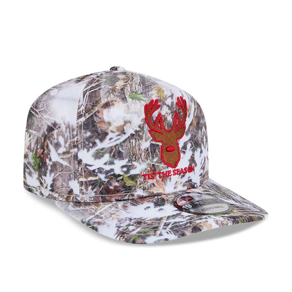 New Era Holiday Essentials Photoreal 19TWENTY Adjustable Cap, three-quarter view showing a red embroidered reindeer logo with 'TIS THE SEASON text on the camo-patterned front panel, featuring a curved visor with a 19TWENTY size sticker.