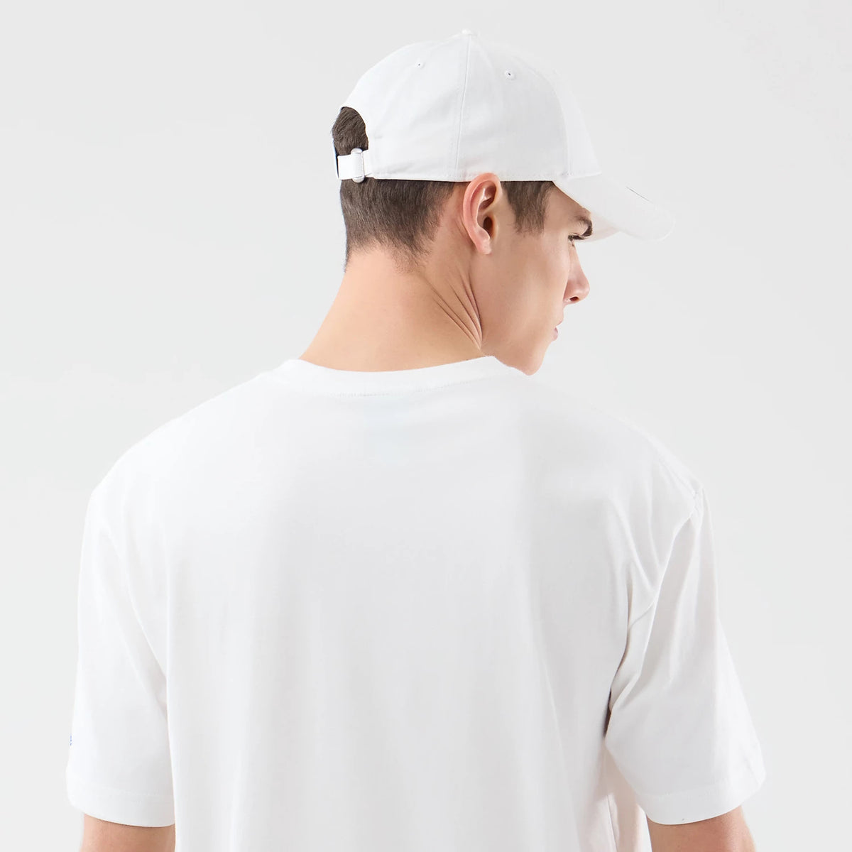 New Era Brooklyn Nets Space Jam 2 X NBA White T-Shirt, back view with a plain white design seen clearly, on-model styling with a matching white cap featuring embroidered eyelets and an adjustable strap closure at the back.