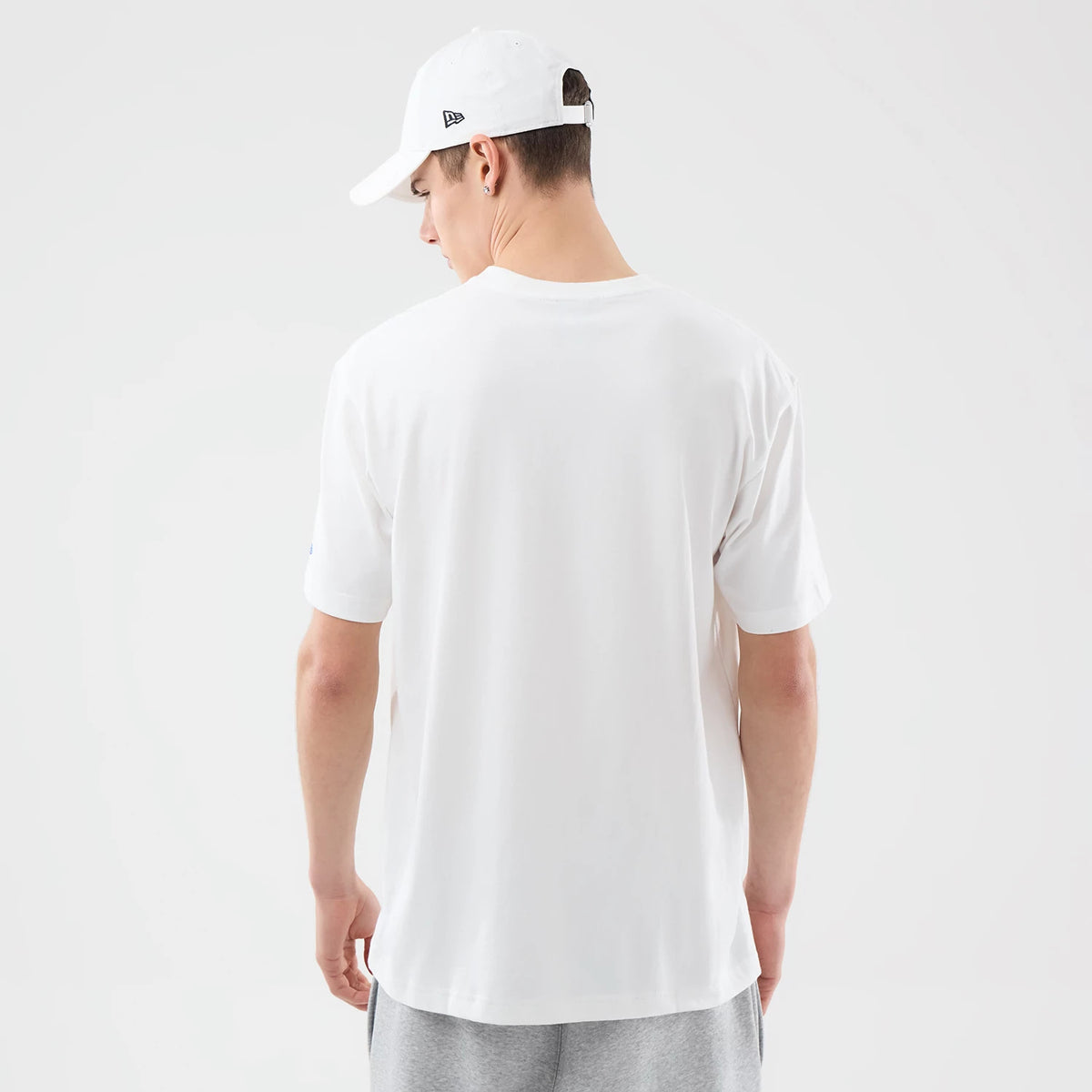 New Era Brooklyn Nets Space Jam 2 X NBA White T-Shirt, back view on-model showing the clean white fabric with plain styling, worn with a white cap featuring a small embroidered New Era logo on the side.